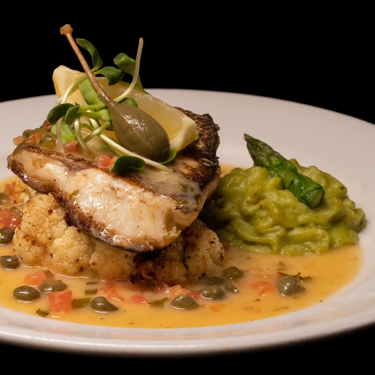Poisson grillé avec une garniture de légumes et une purée d’asperges sur une assiette blanche