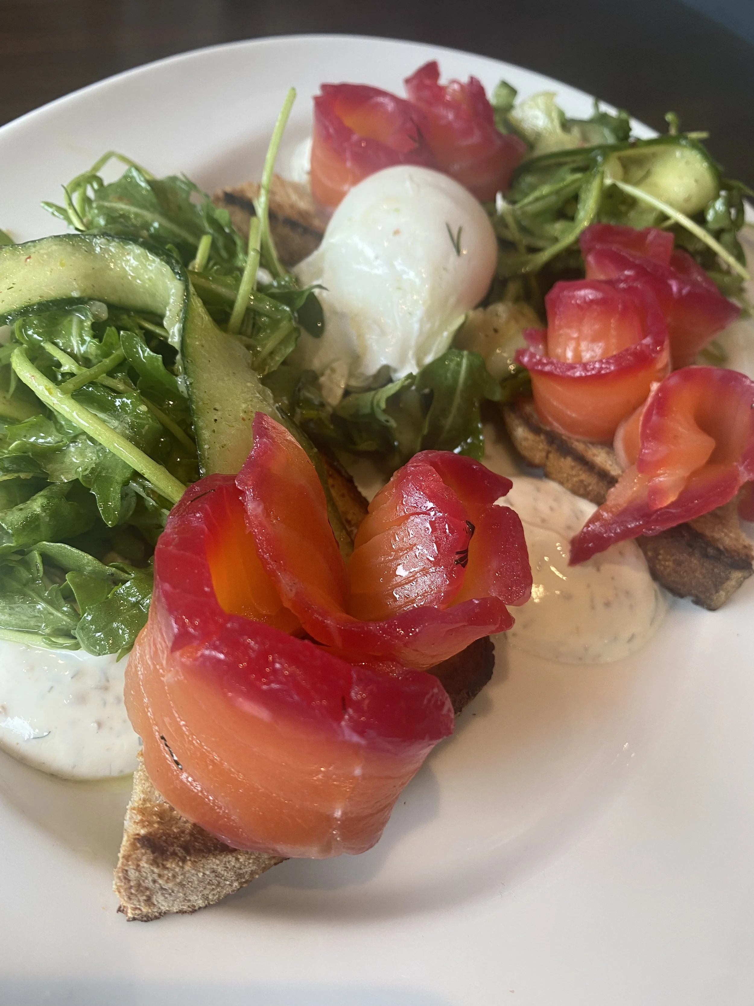 Tartine avec saumon fumé, œuf mollet, concombre, tomates, salade verte, et sauce
