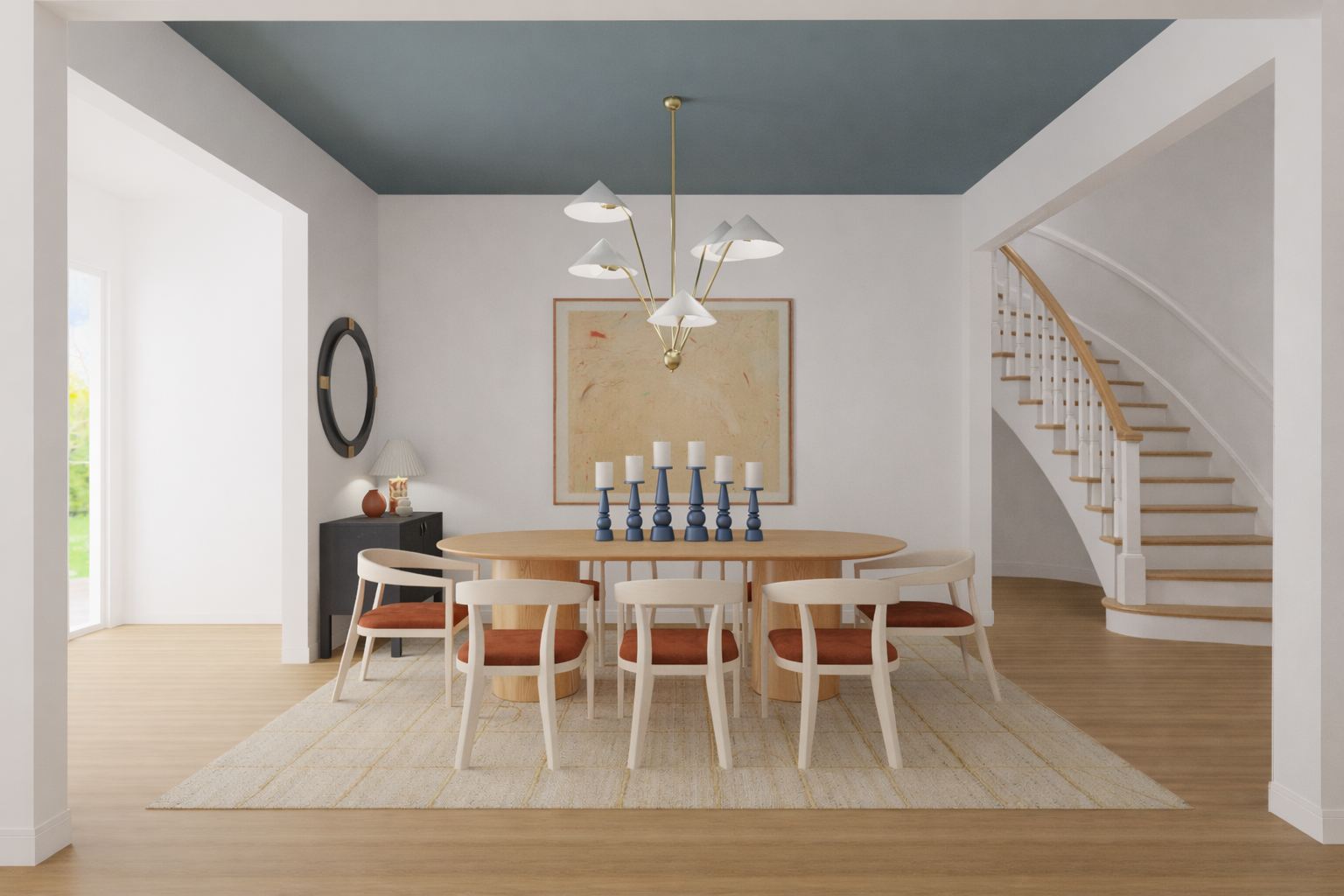 A modern dining room with an oval wooden table, six white chairs with reddish-brown cushions, and blue and white candles on the table. There is a chandelier with multiple white shades hanging above. A beige abstract painting is on the wall behind. Th