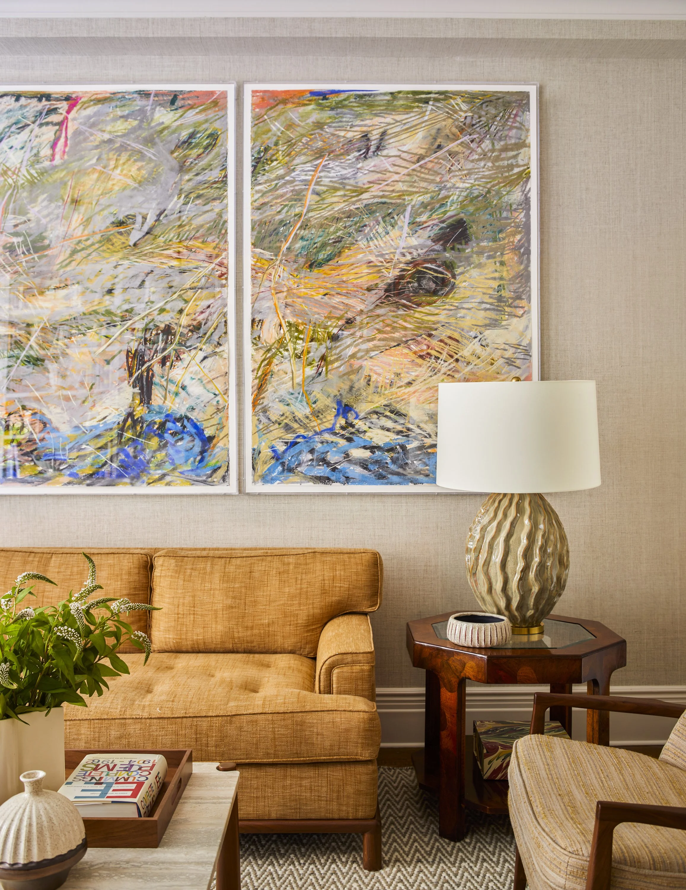Living room with abstract art, beige sofa, lamp, and wooden coffee table with decor