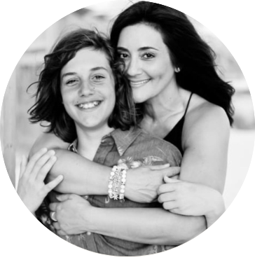 A woman and a girl hugging and smiling in a black-and-white photo.