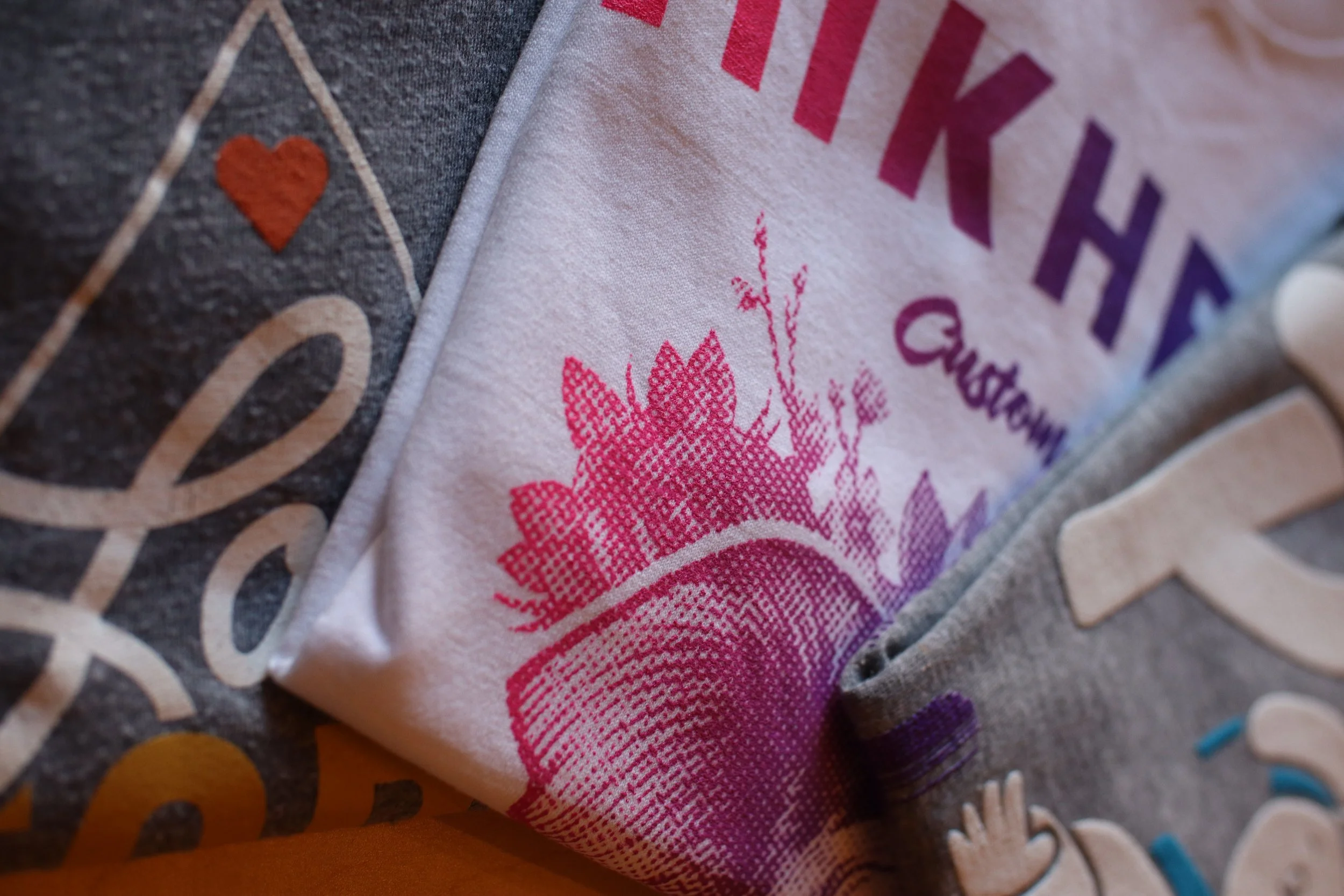 Custom screen-printed graphic t-shirts with vibrant designs, folded and ready for retail, produced by MOAB for apparel branding in El Paso, TX.