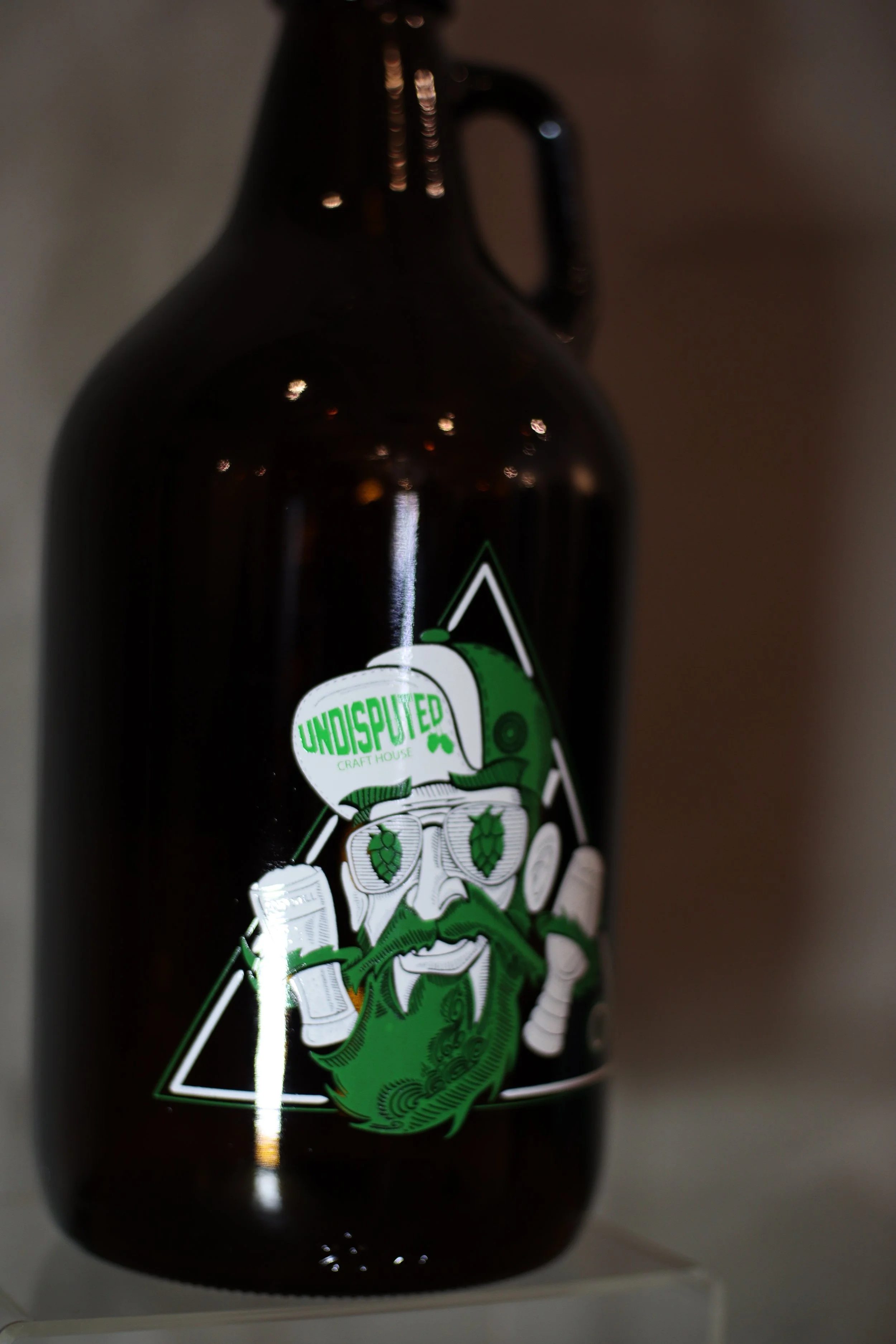 A dark brown beer bottle with a colorful label featuring a green cartoonish caricature of a bearded man with glasses. The label includes the word "Undisputed" in bright green letters and other small text.
