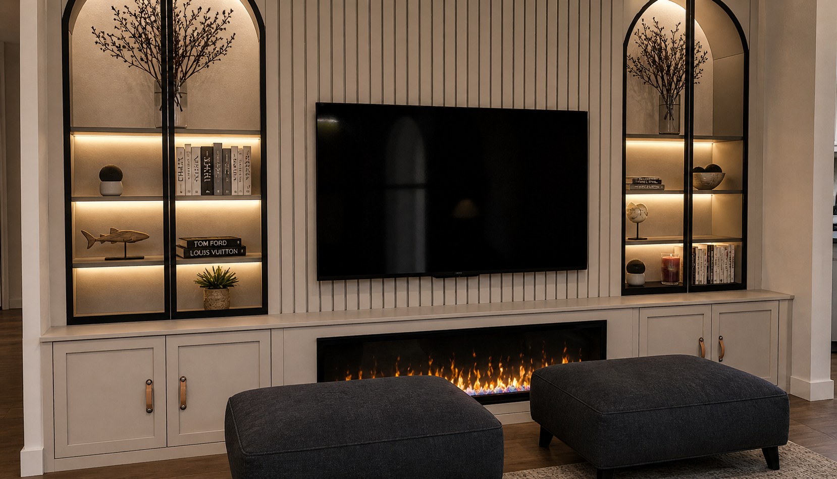 Living room entertainment wall with built-in shelves, a large flat-screen TV, and an electric fireplace.