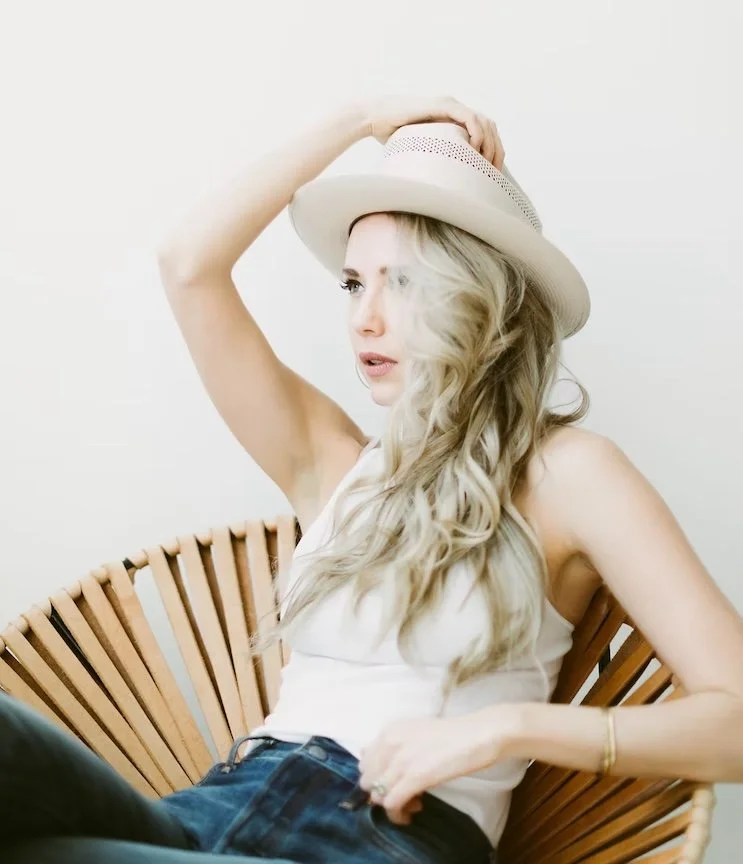 woman in a cowboy hat sitting in a modern chair