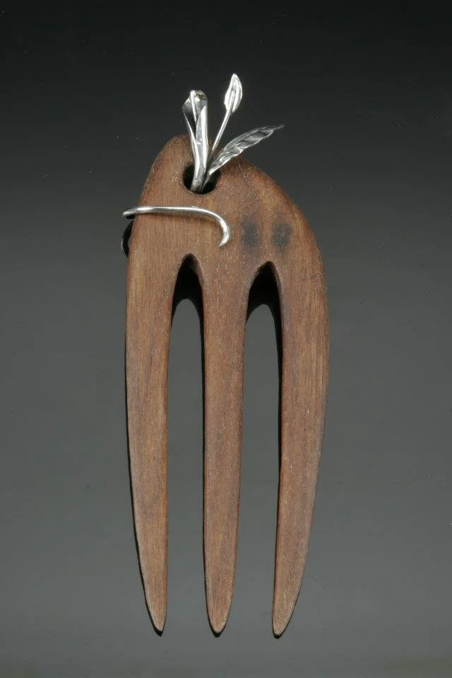 a wooden comb with silver leaves and buds emerging from it