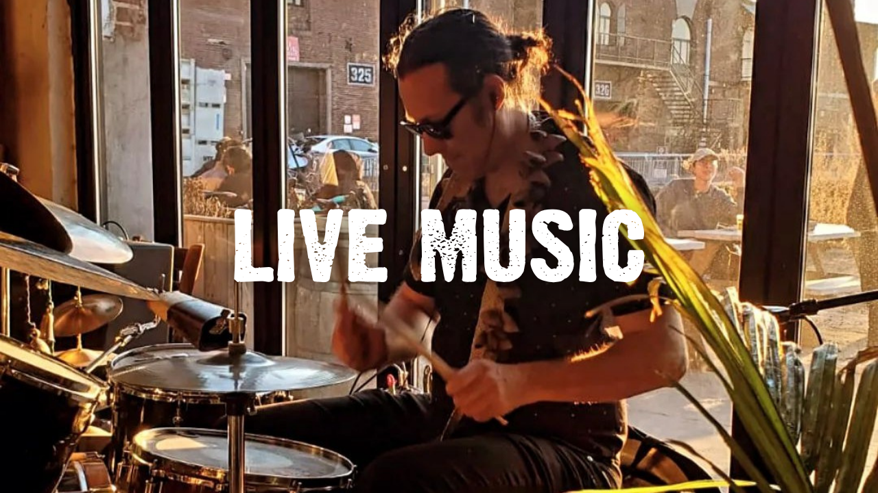 Live Music with a person playing drums in front of a taproom window