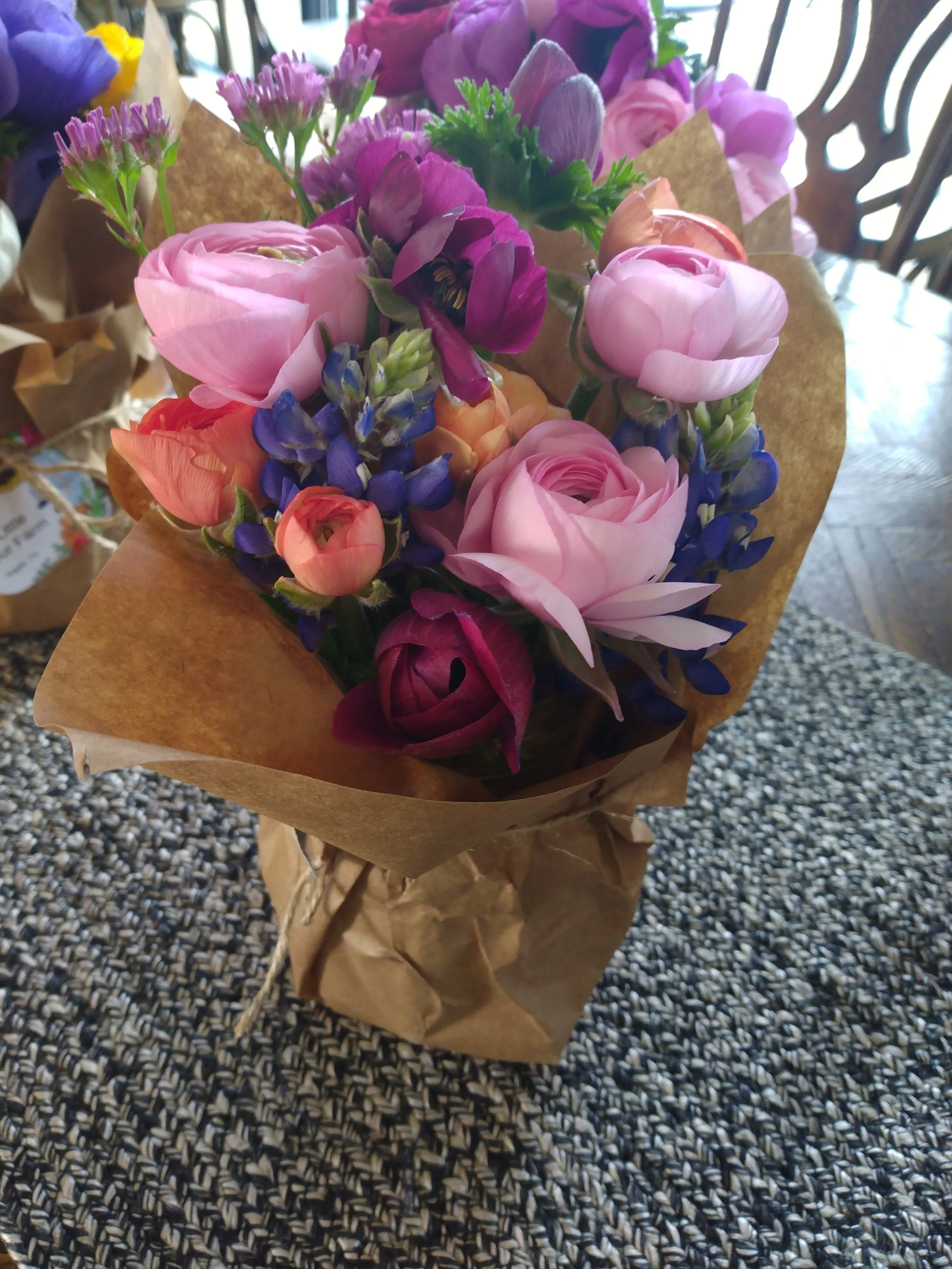 Ranunculus, anemone, statice, and bluebonnet paper wrapped mason jar bouquet
