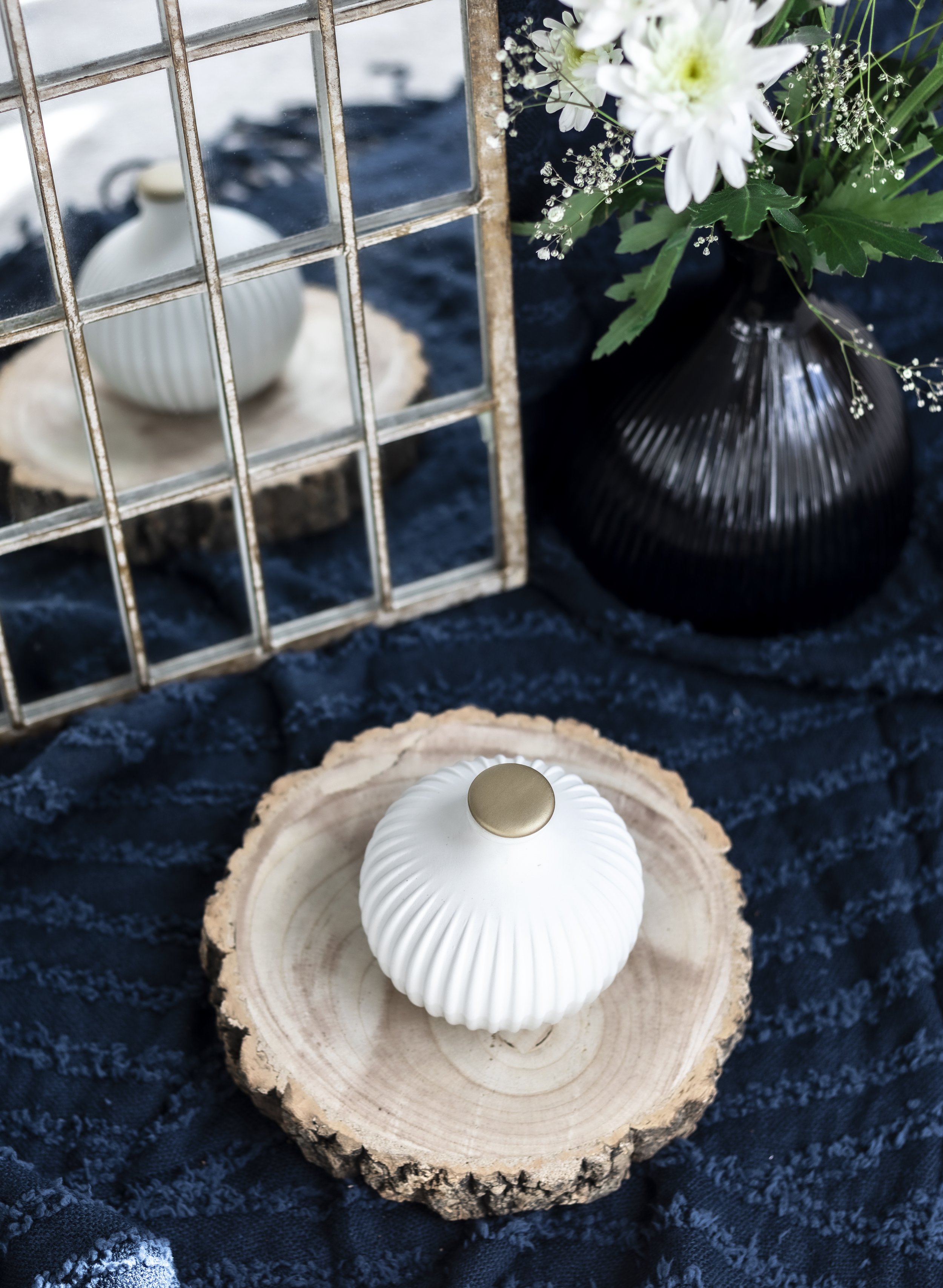 Vase on wooden slice with mirror and flowers