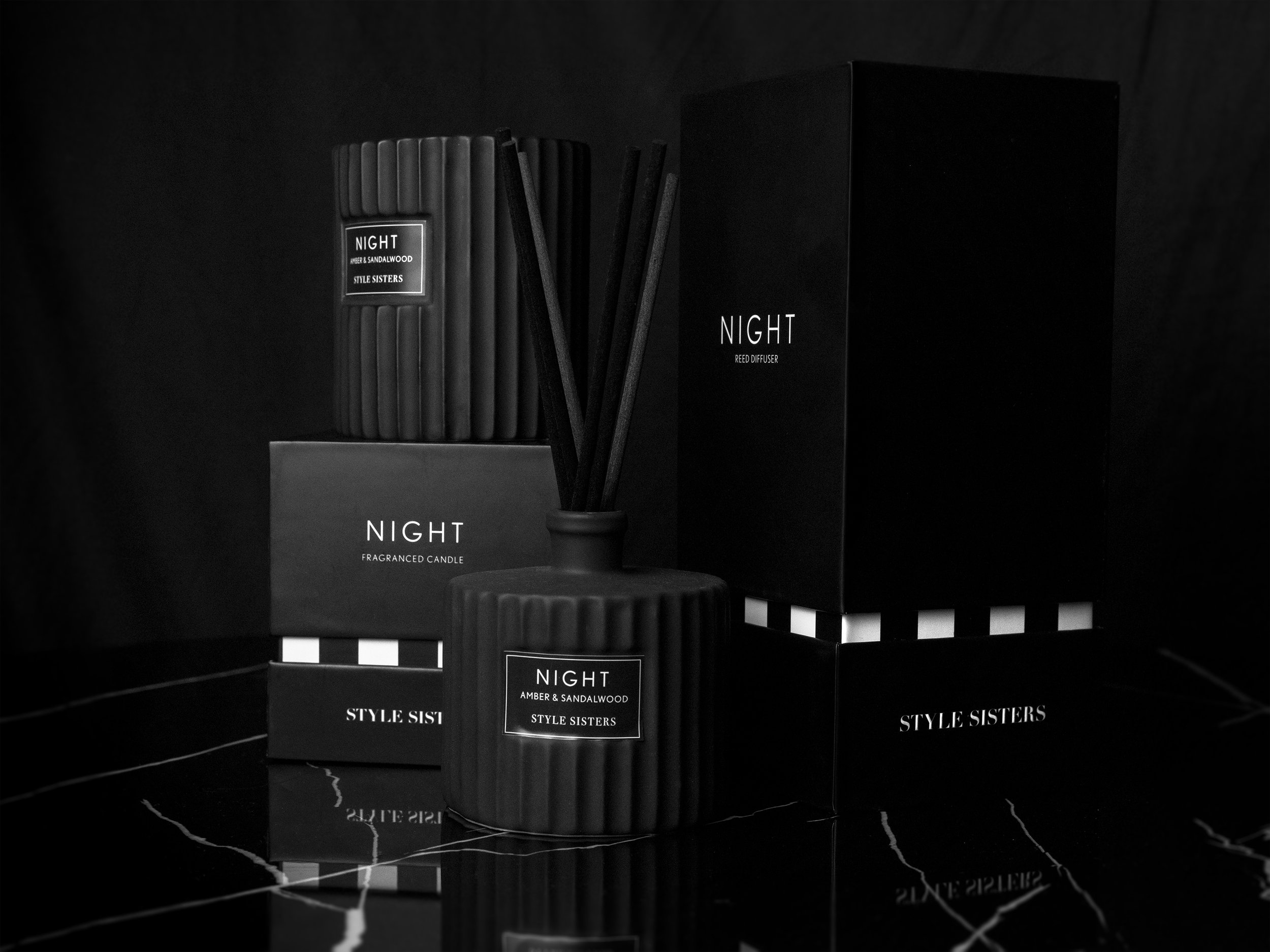 Black candle and reed diffuser labeled 'Night' with packaging, set on a marble surface.