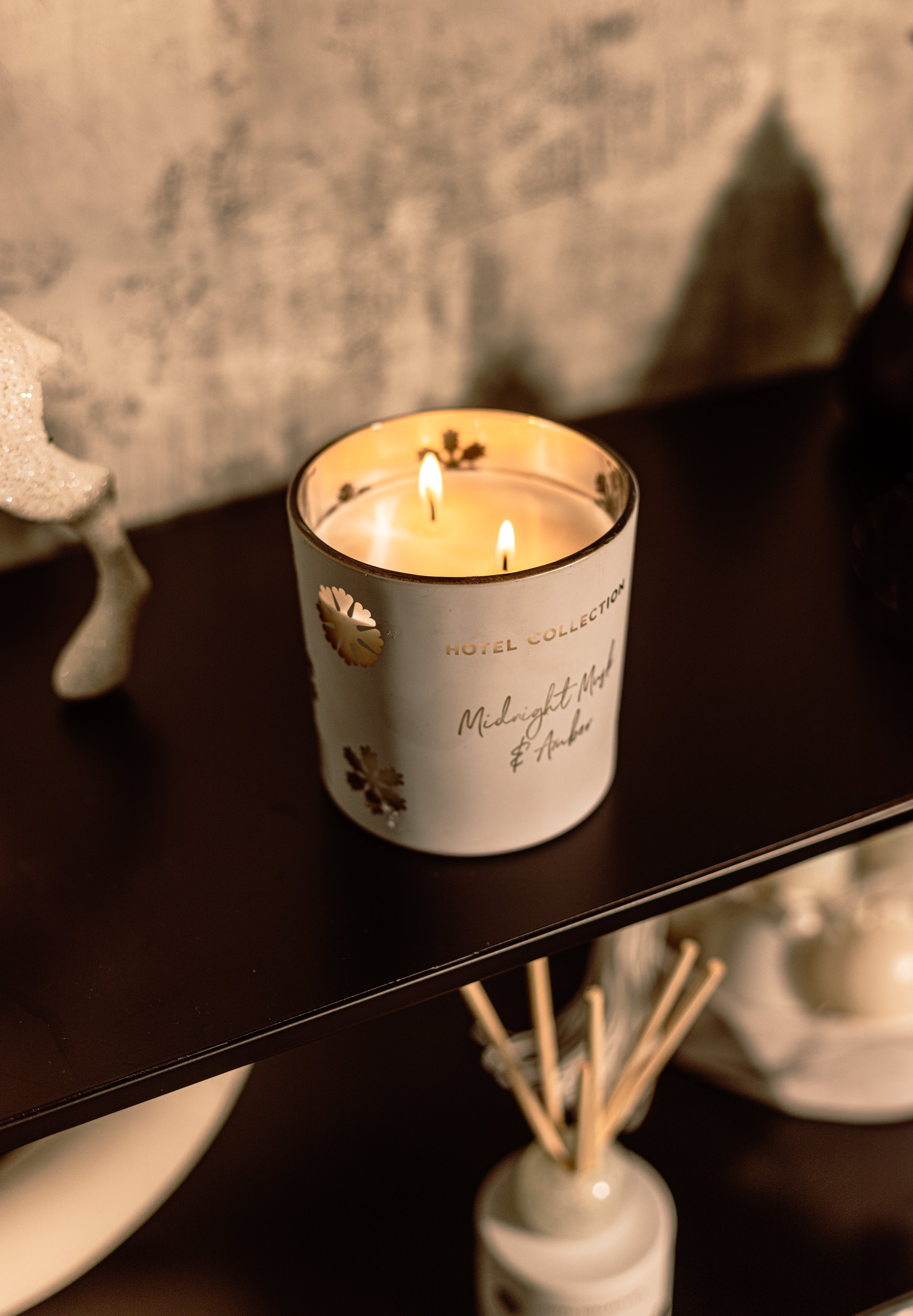 Lit candle on a shelf with decorative label "Midnight Musk & Amber."
