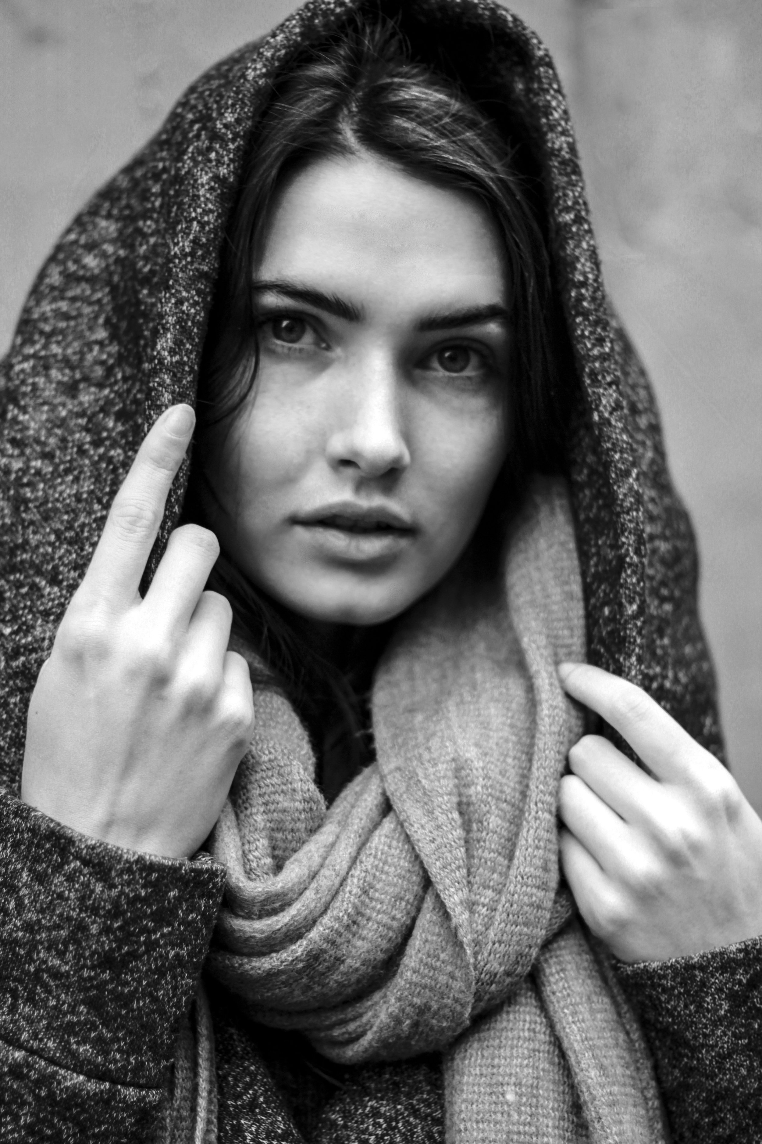 Black and white portrait of a person wearing a hooded coat and scarf.