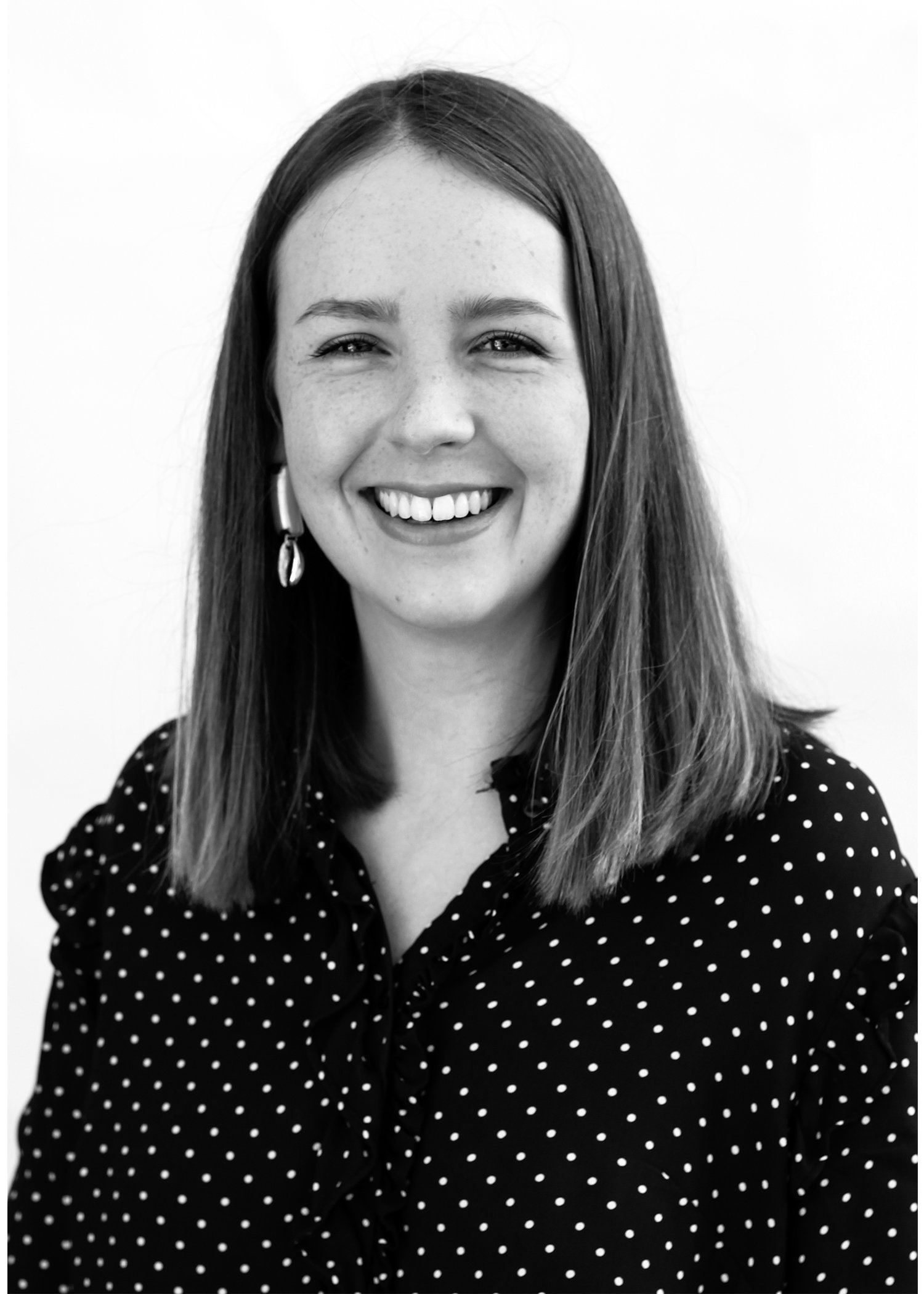 Smiling woman in polka dot blouse, black and white photo.