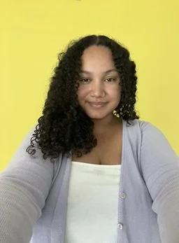 Young woman with curly hair smiling at camera