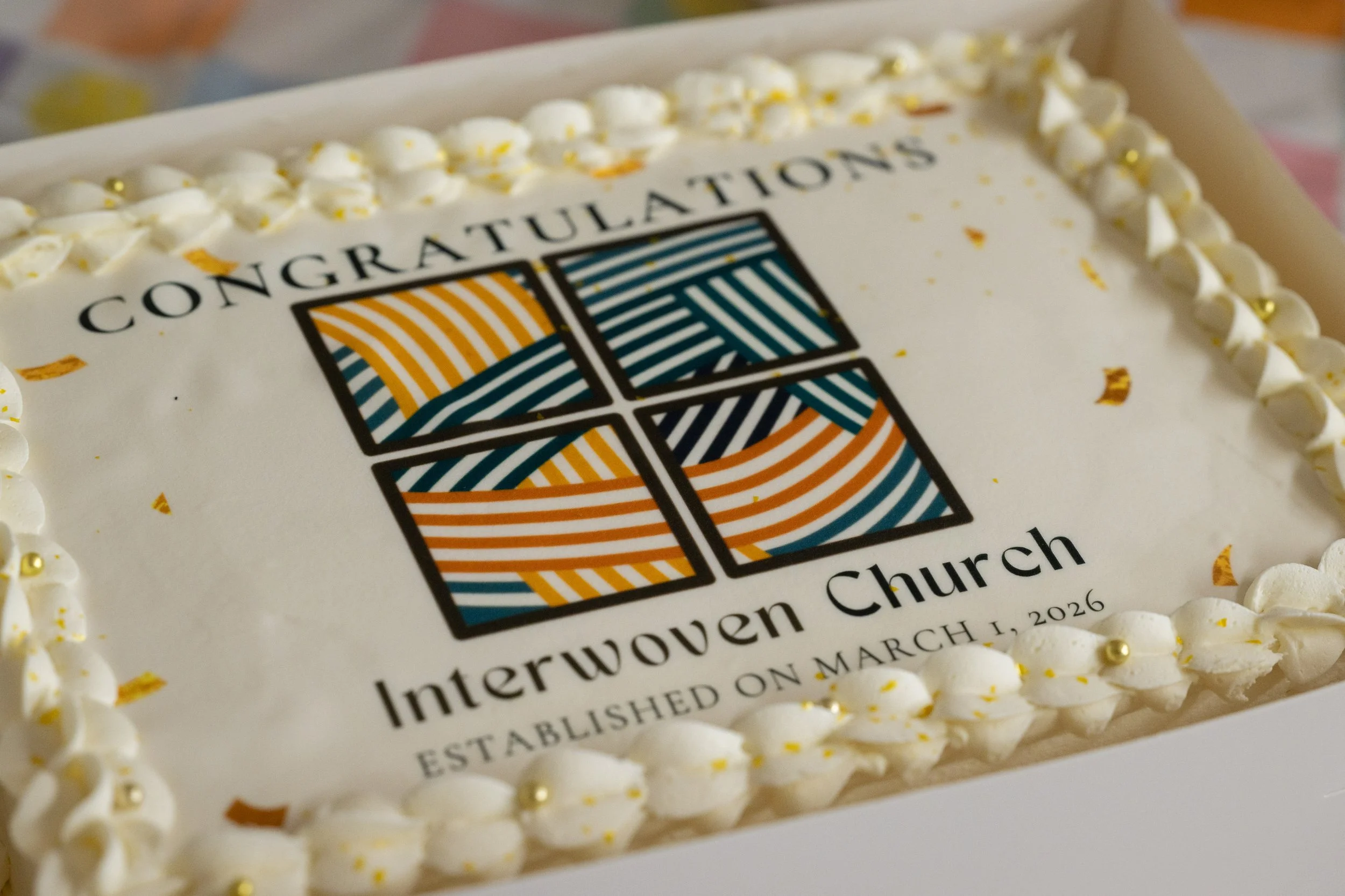 A decorated cake with the Interwoven Church logo and text celebrating its establishment on March 1, 2026.