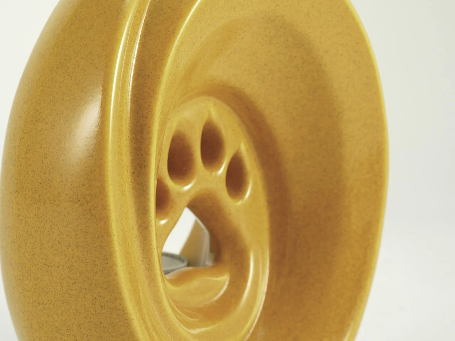 Amber-finished ceramic pet urn with tealight candle holder and paw-shaped cutout, crafted in Europe.