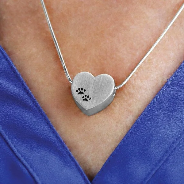 Pewter heart-shaped pendant with black paw prints, matching 19-inch chain, and discreet memento compartment.