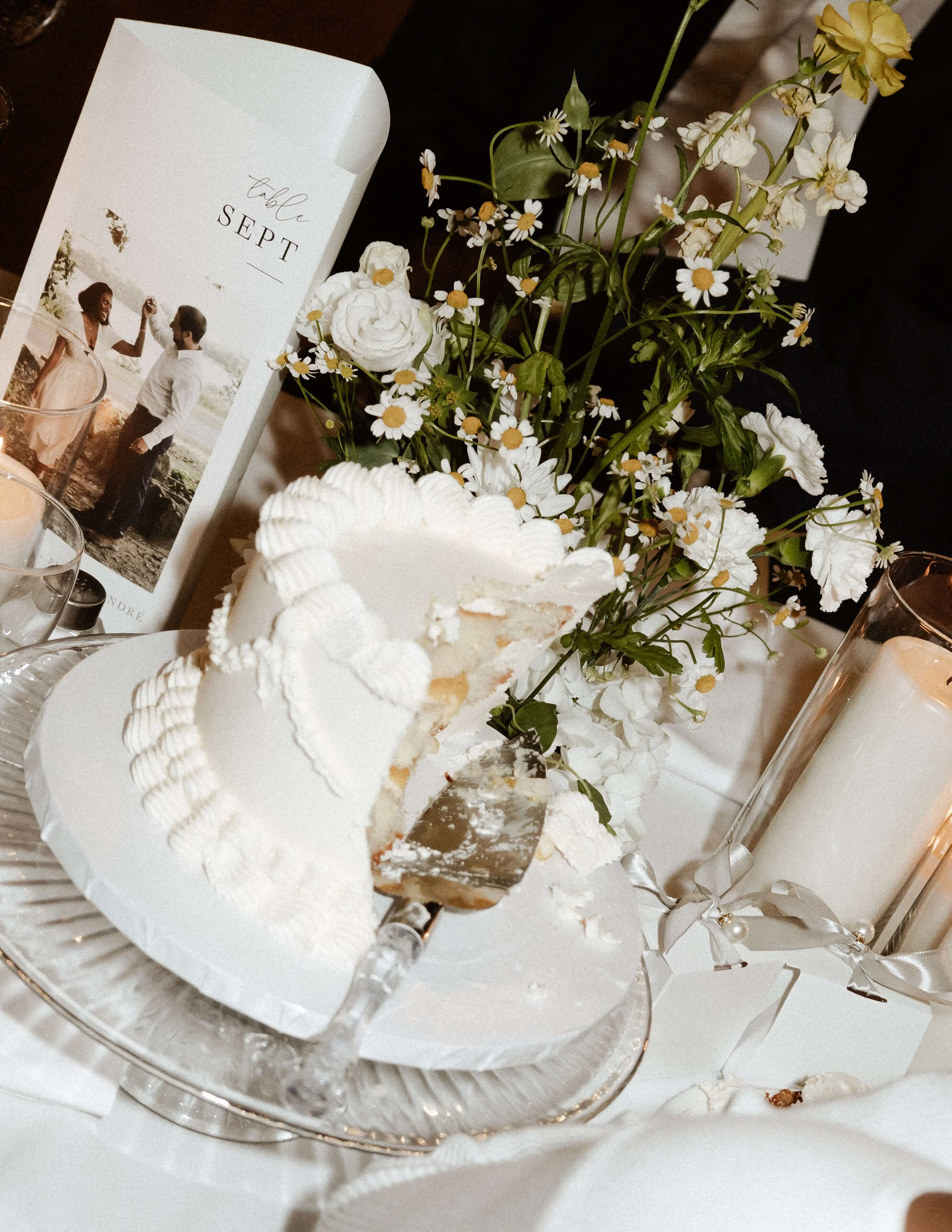 Photographie argentique d’un gâteau de mariage coupé avec des fleurs et un numéro de table en arrière-plan