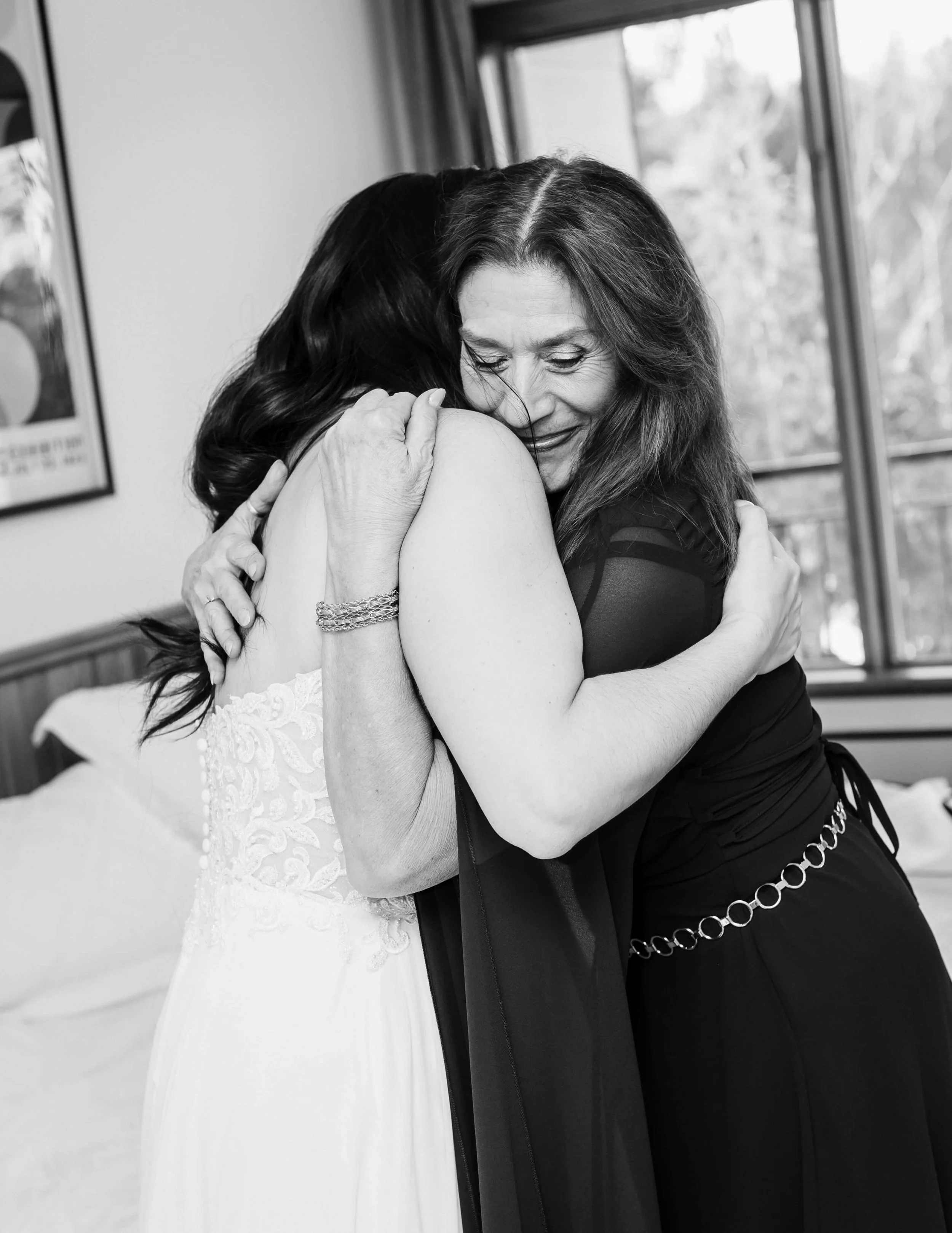 Une mariée et sa mère se prennent dans leurs bras.