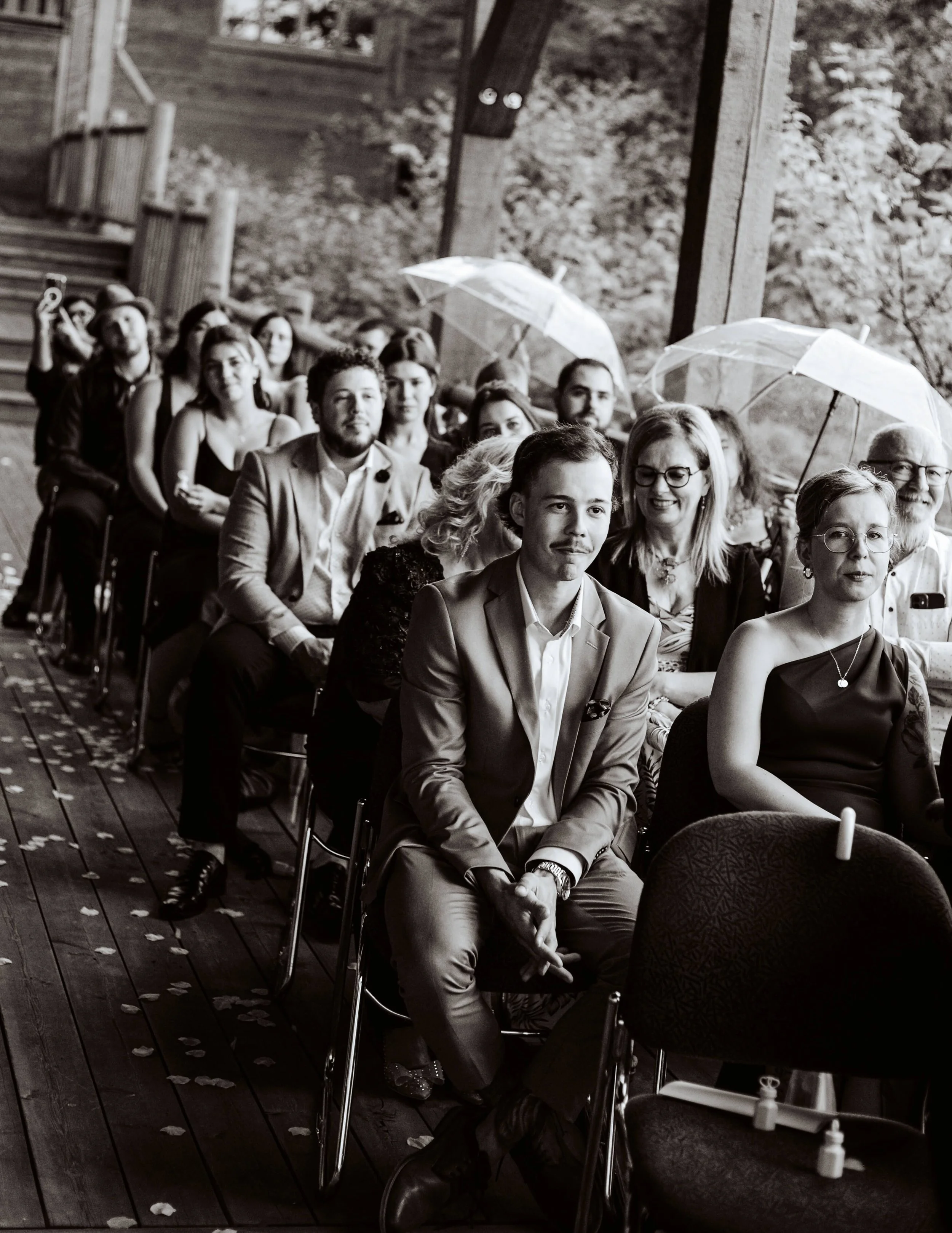 Invités assis cérémonie mariage extérieur avec parapluies, photo noir et blanc
