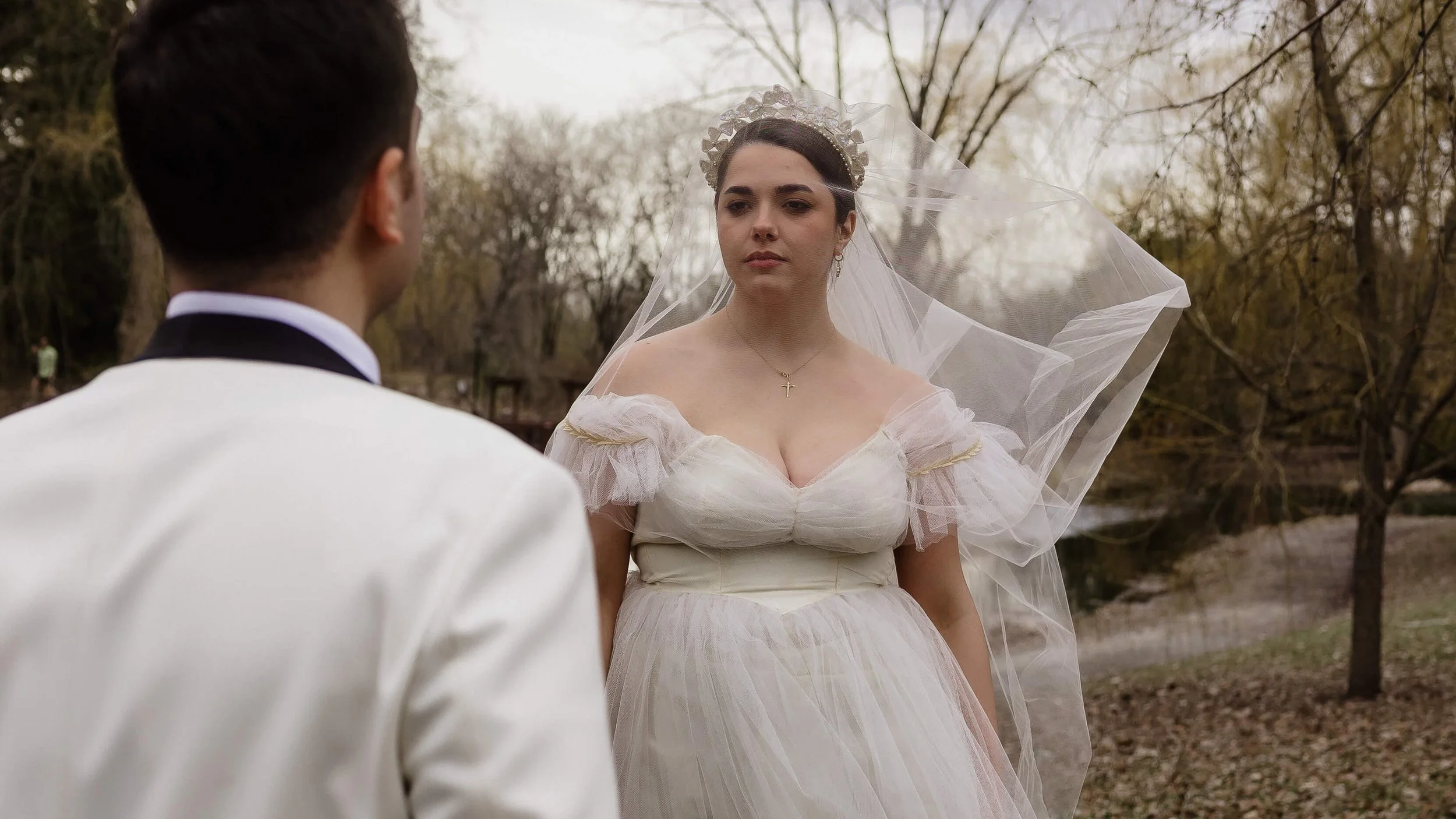 Une femme en robe de marié regarde son marie. Son voile est par dessu son visage.