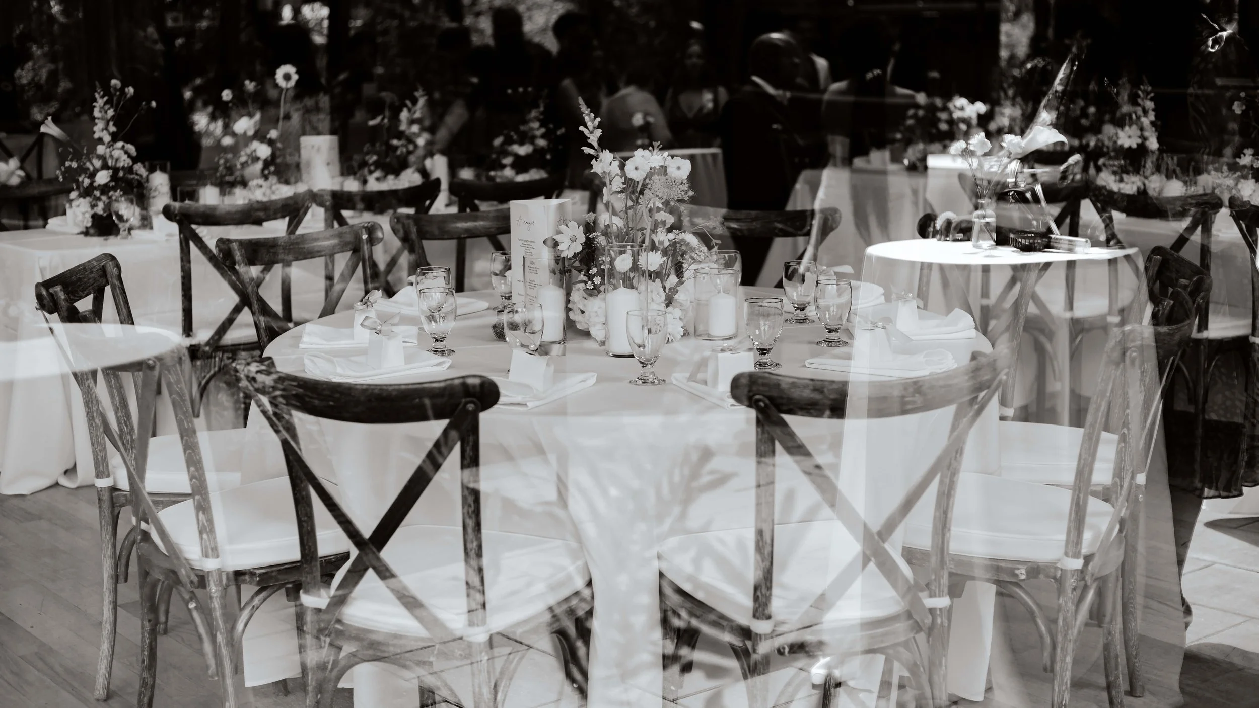 Photo noir et blanc d'une table de mariage prise au travers d'une fenêtre