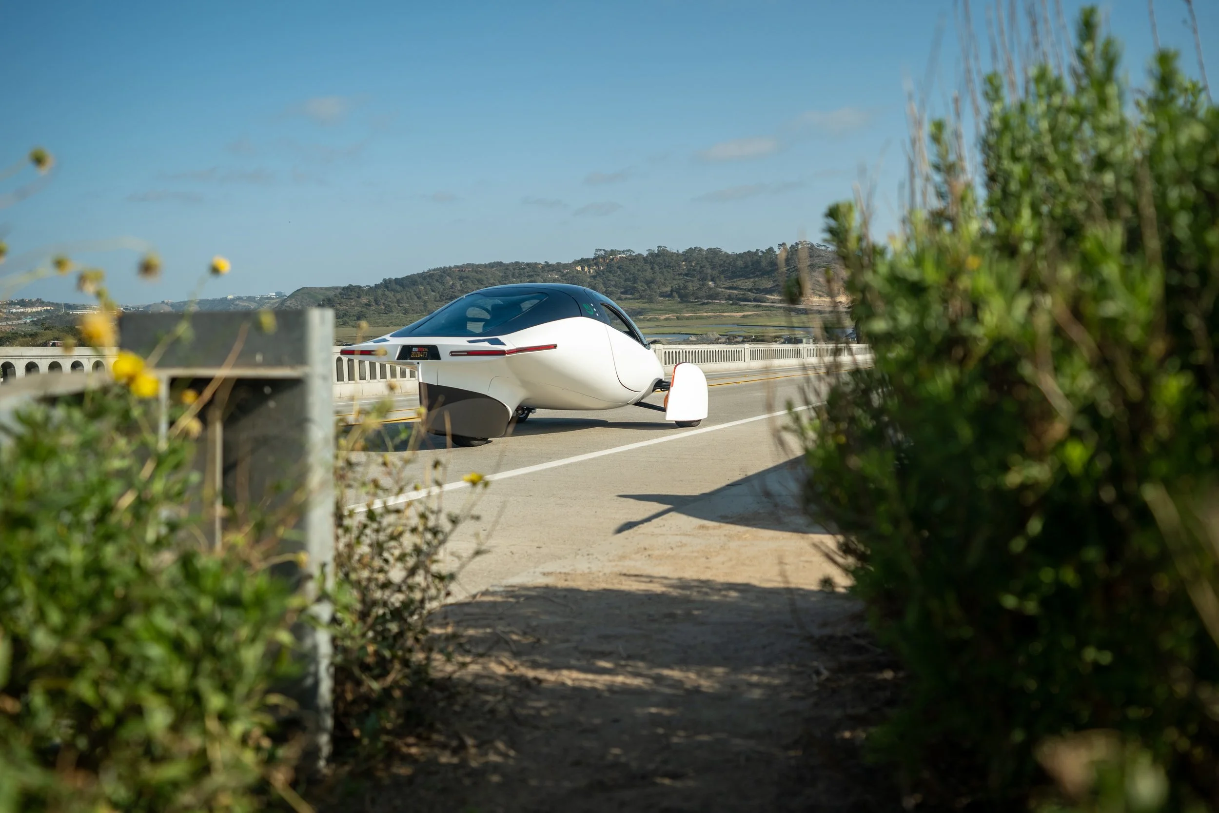 Lifestyle photo of the Aptera vehicle out in nature with flowers