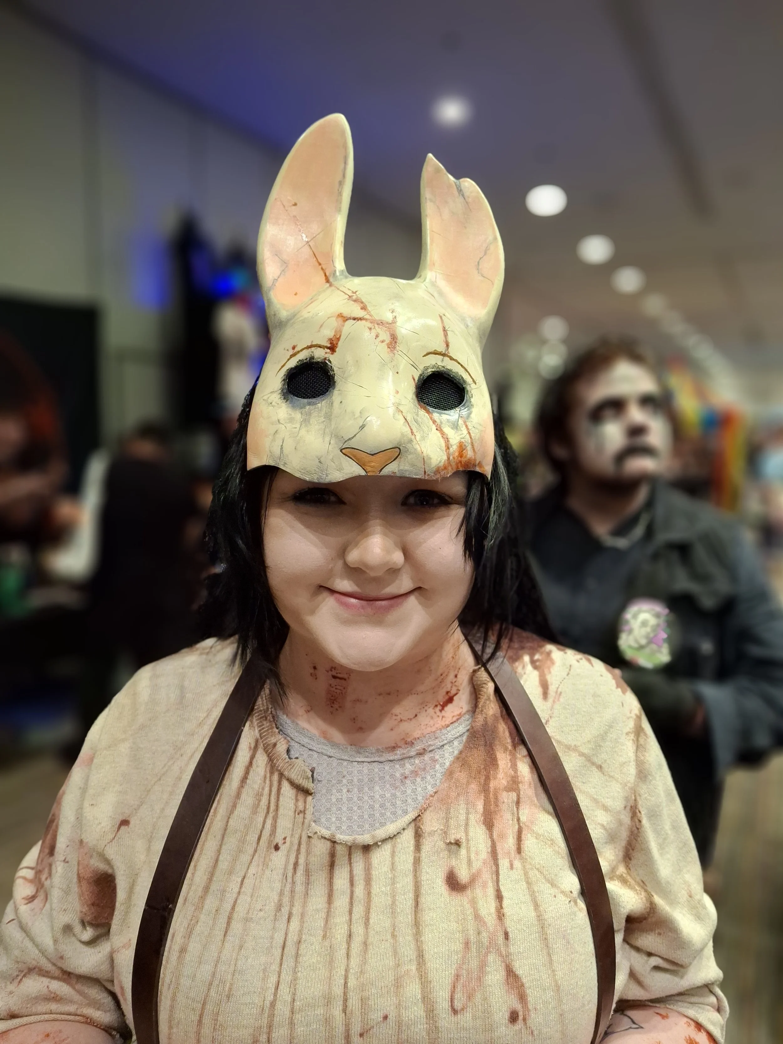 Person wearing a creepy bunny mask, blood-stained shirt, and apron at a costume event.