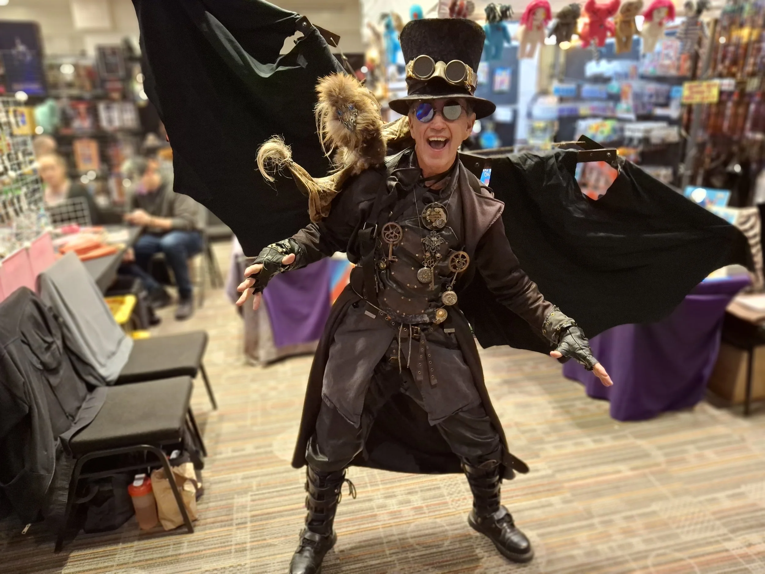Person dressed as a steampunk vampire with a top hat, goggles, and a lizard on their shoulder, inside a store.