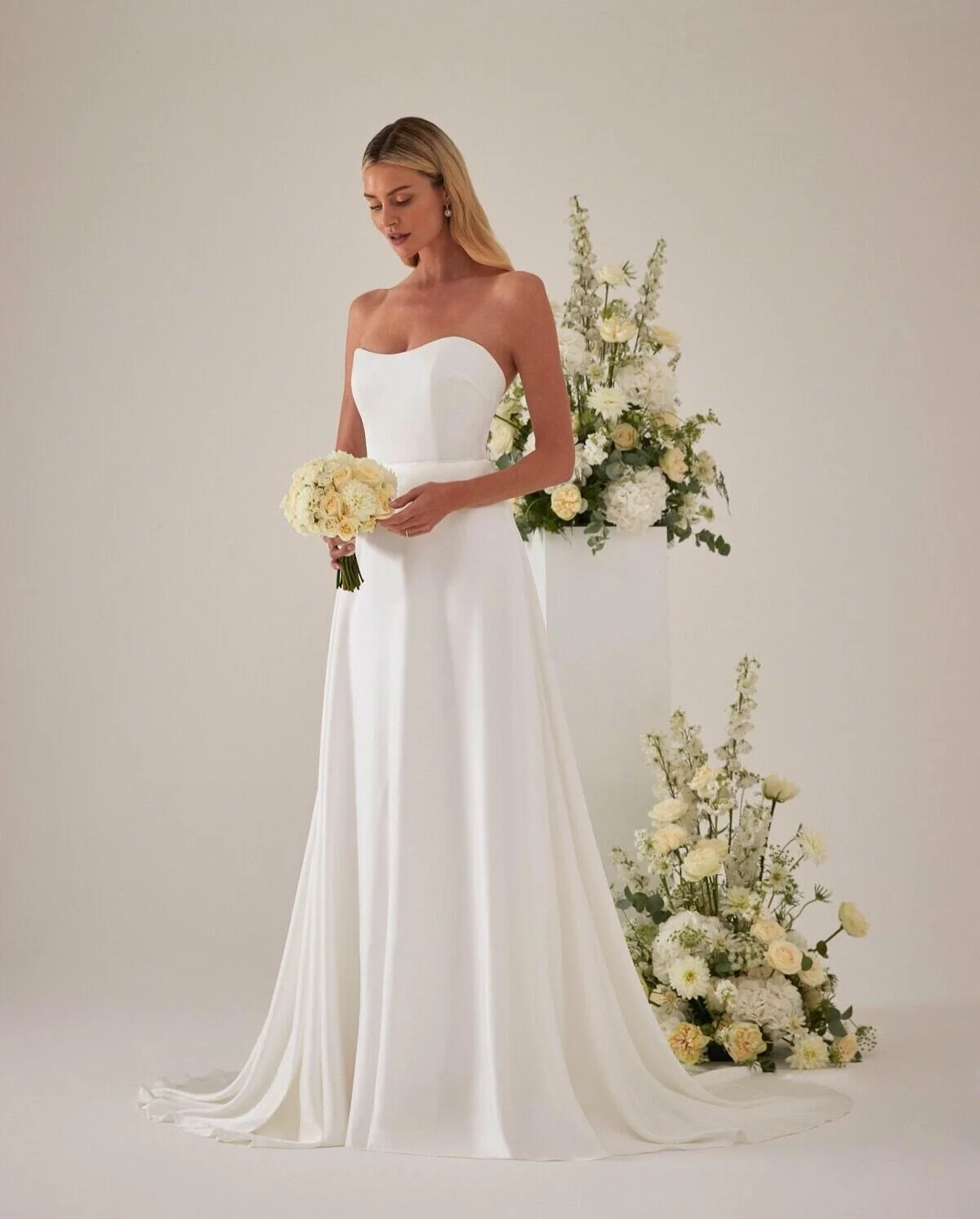 Coming Soon to Gamberdella 🤍

Connie-Mae by Sassi Holford is a study in understated elegance. A beautifully moulded crepe bodice with a soft smile neckline pairs effortlessly with a slim A-line satin crepe skirt. Defined by clean lines and refined s