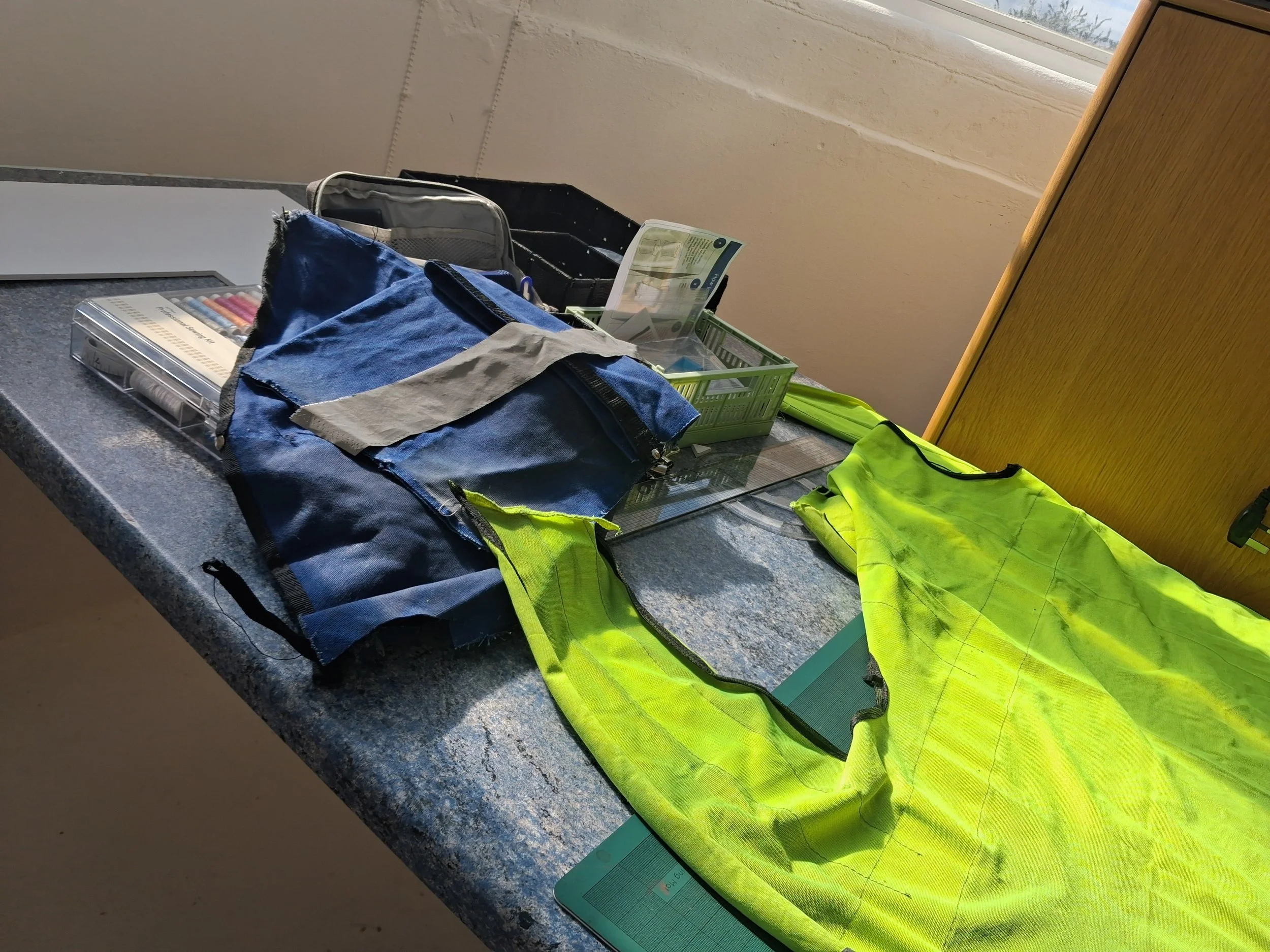 A desk with various items including a safety vest, a high-visibility yellow shirt, toolboxes, and a pack of colored pens.