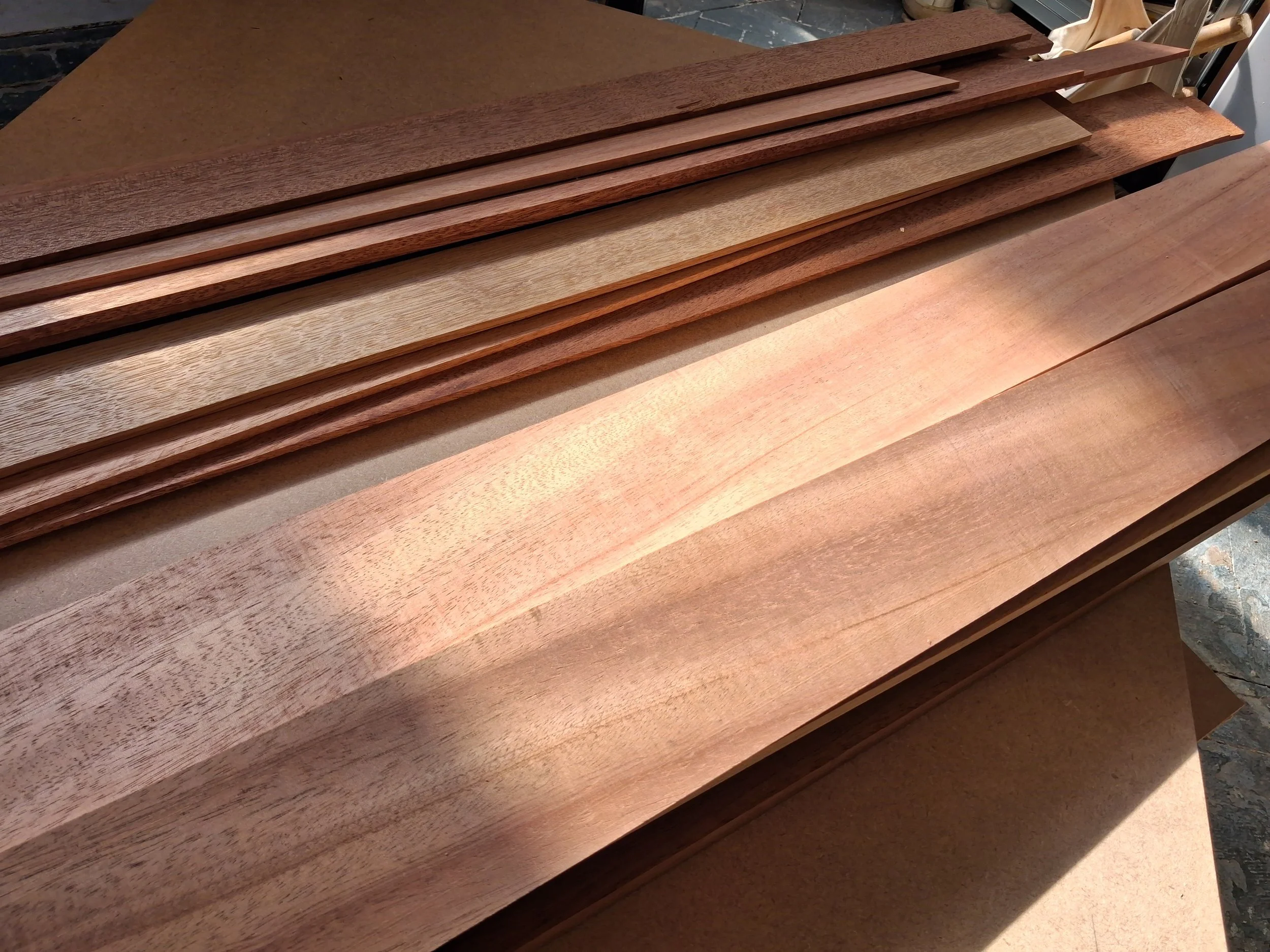 Stack of wooden planks of various shades and grains on a workbench.