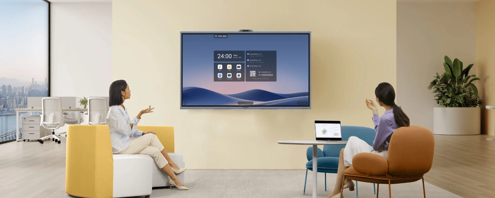 Dos mujeres conversando en una sala de reuniones con un gran pantalla LED y una laptop en una mesa. Ventana con vista a la ciudad al fondo.