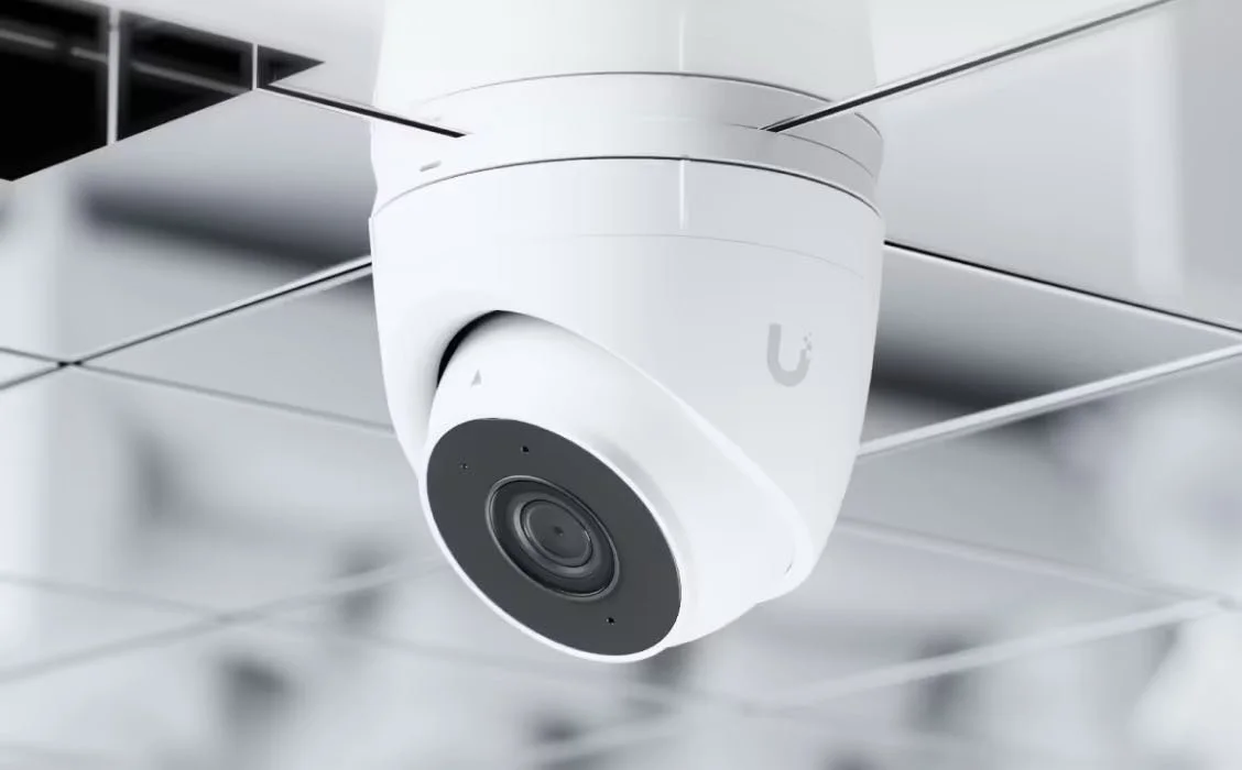Una cámara de seguridad moderna instalada en un techo de rejilla metálica.