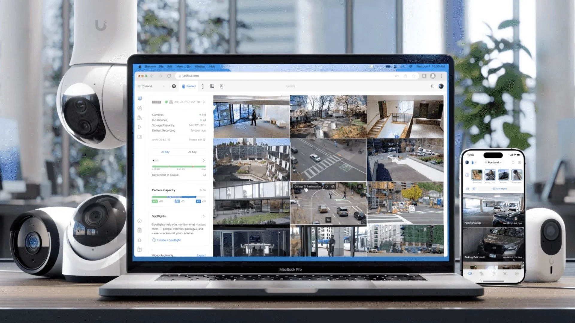Sistema de cámaras de seguridad conectadas a una computadora portátil y teléfono móvil, monitoreando diferentes áreas exteriores e interiores de un edificio.