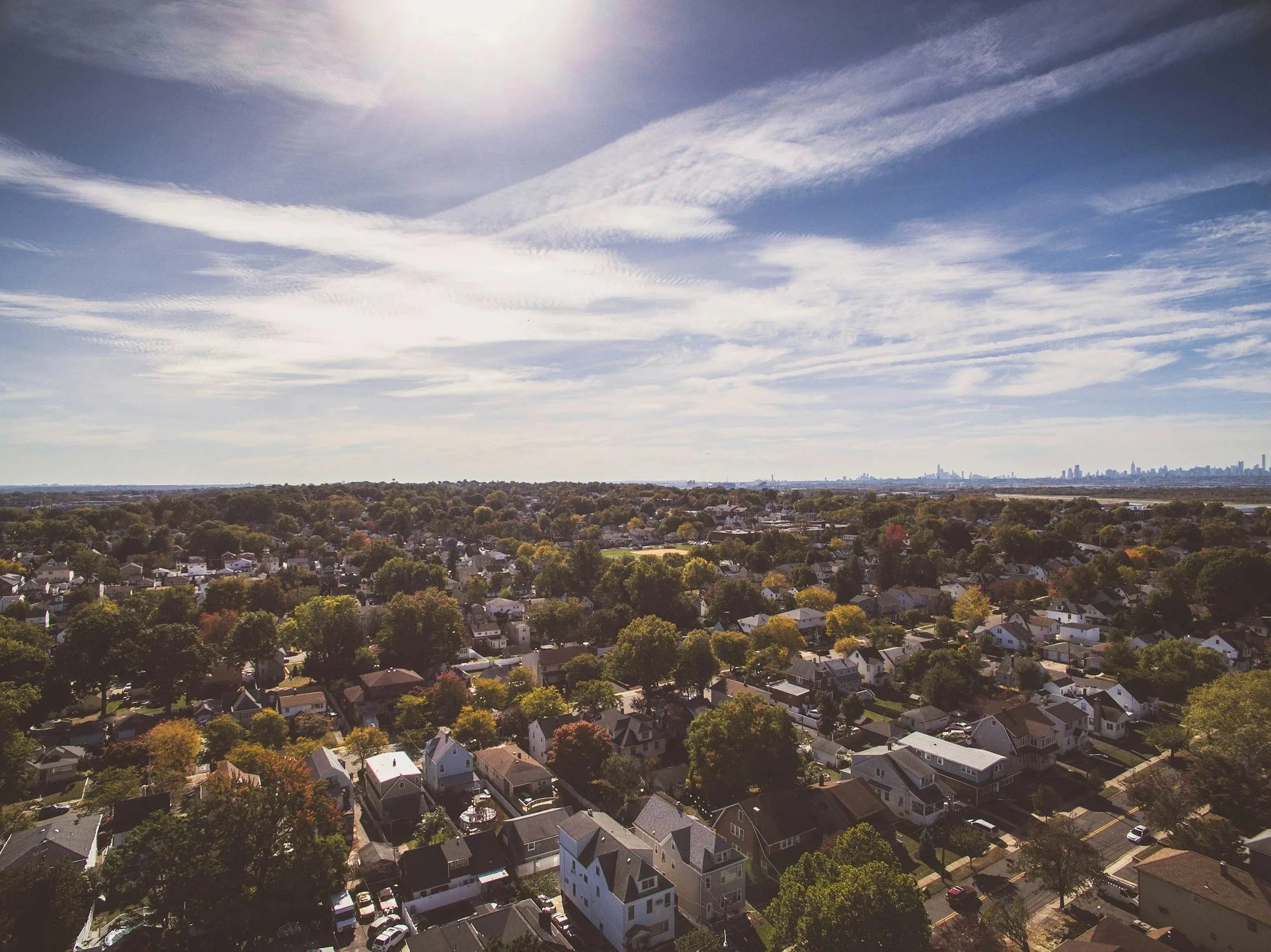 A skyline view of a neighborhood and long, thin clouds streaked across the sky.
