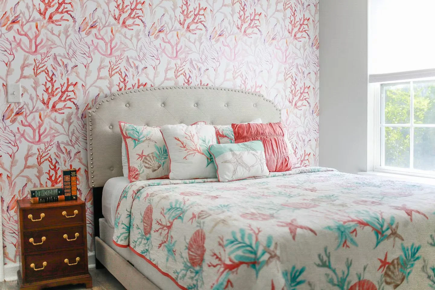 Closeup view of a bedroom with coral reef wallpaper and under water themed bedding.