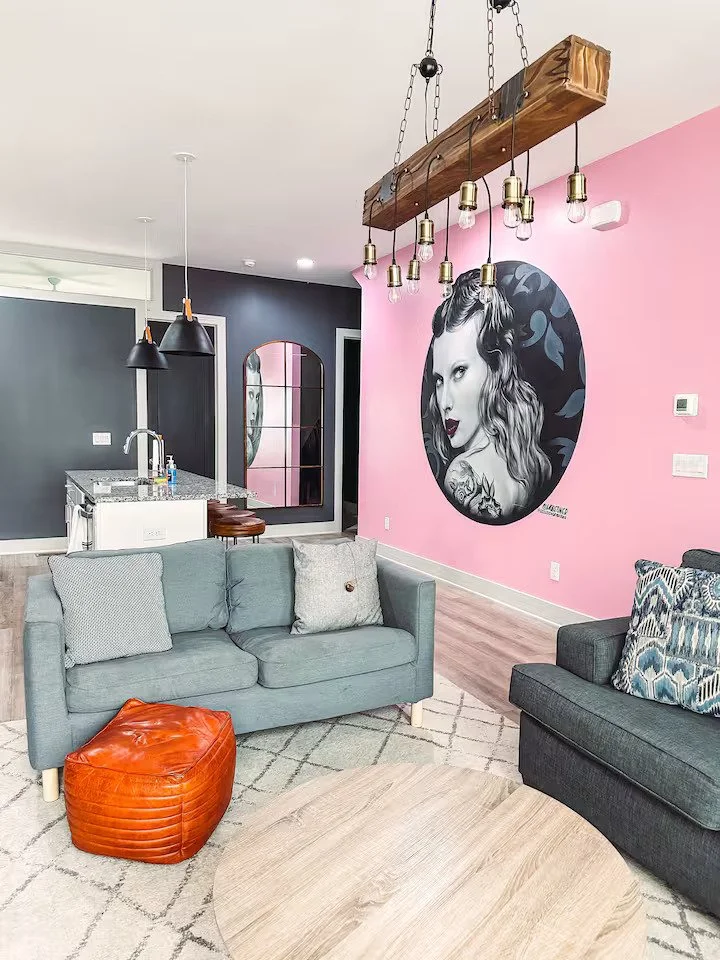 A large painting of Taylor Swift on a pink wall facing the kitchen and living room.