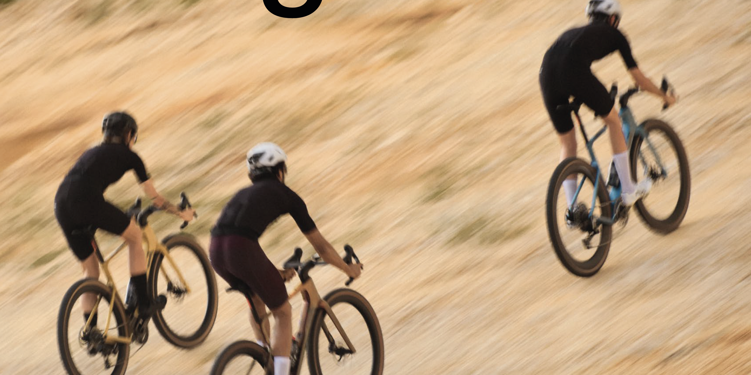 Drei Fahrradfahrer in Bewegung auf einer unebenen, trockenen Wiesenfläche, alle tragen Helme und sportliche Kleidung.