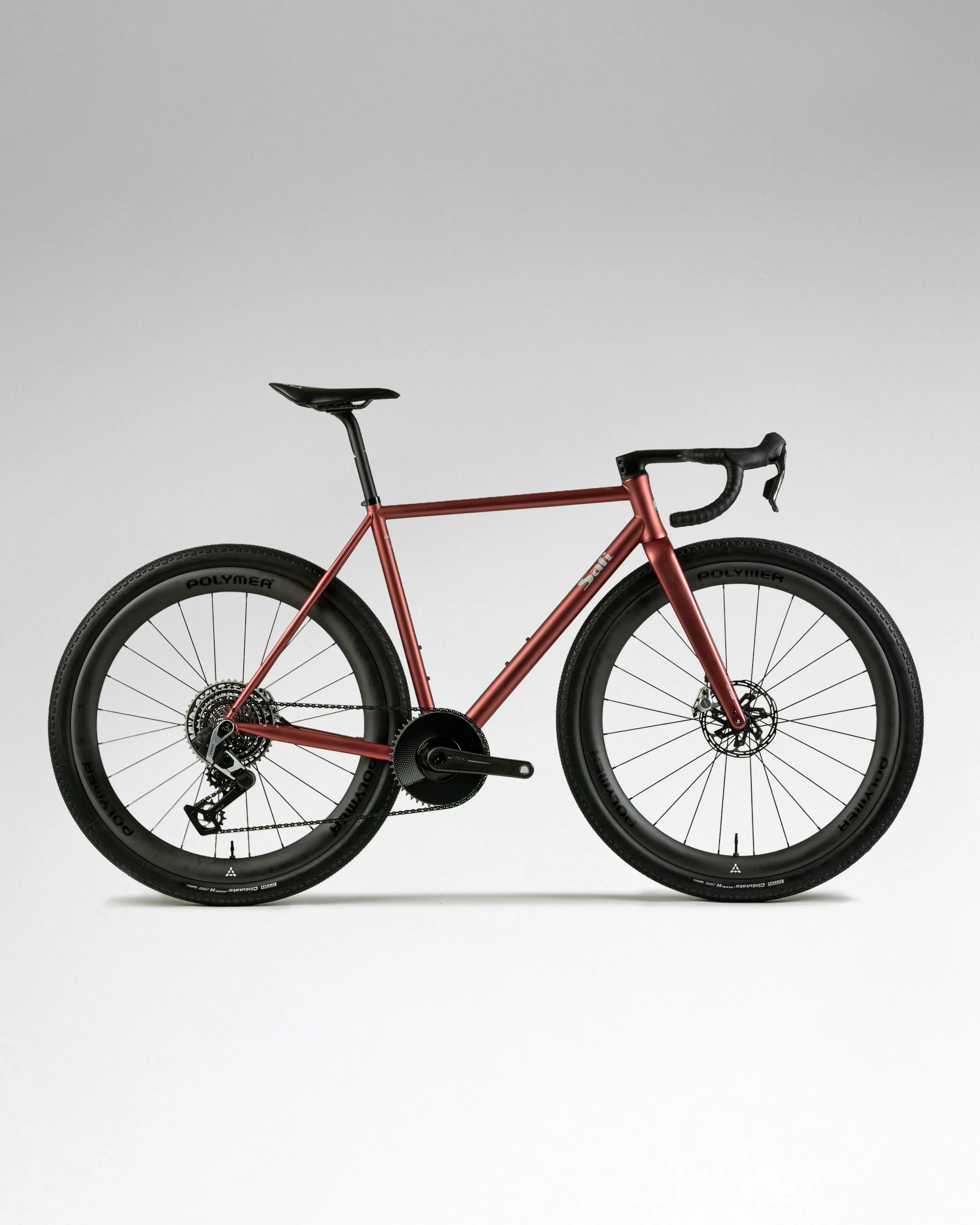 Ein rotes Rennrad mit schwarzen Reifen und einem schwarzen Sattel, abgebildet gegen eine weiße Wand.