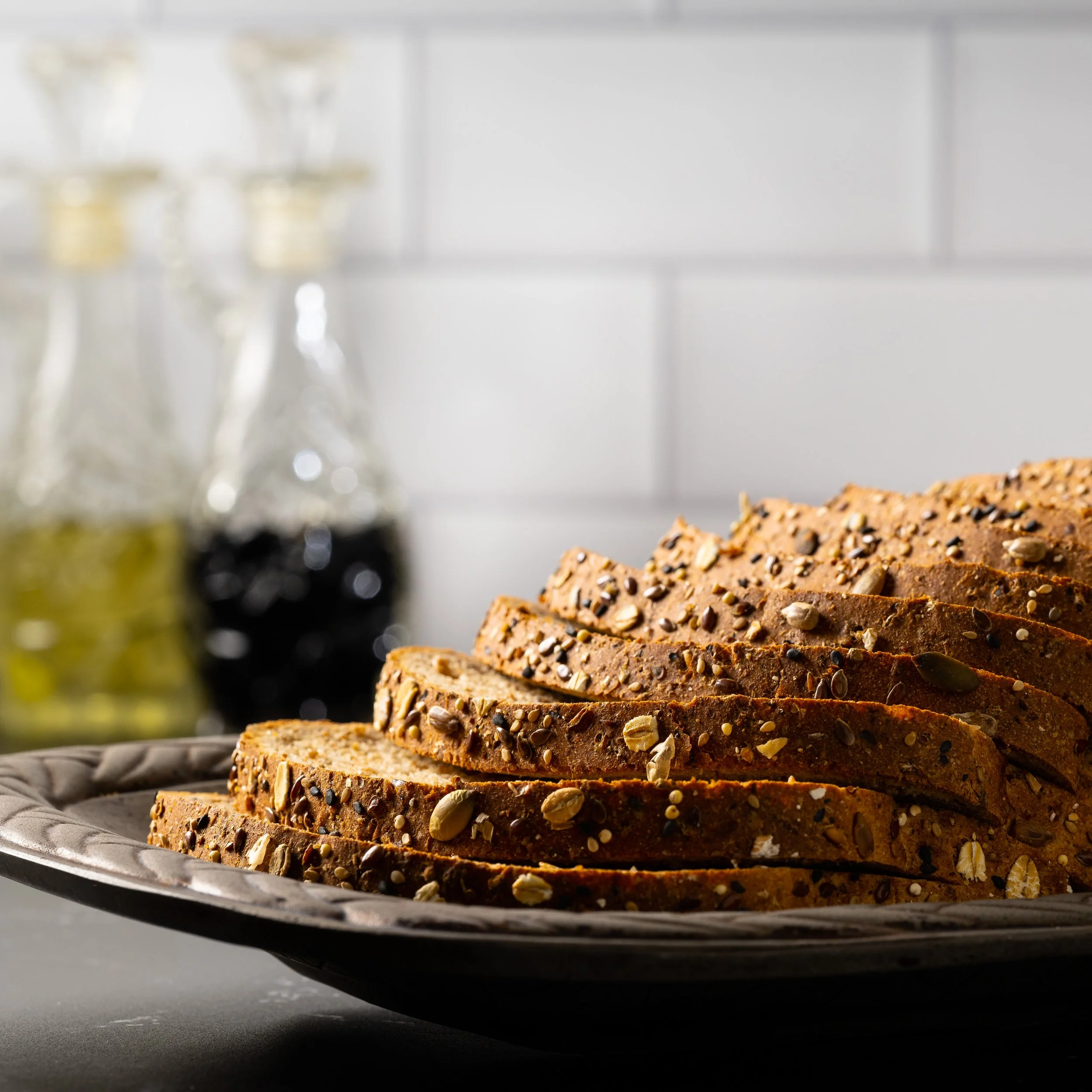 Sliced multigrain bread topped with seeds on a decorative plate.