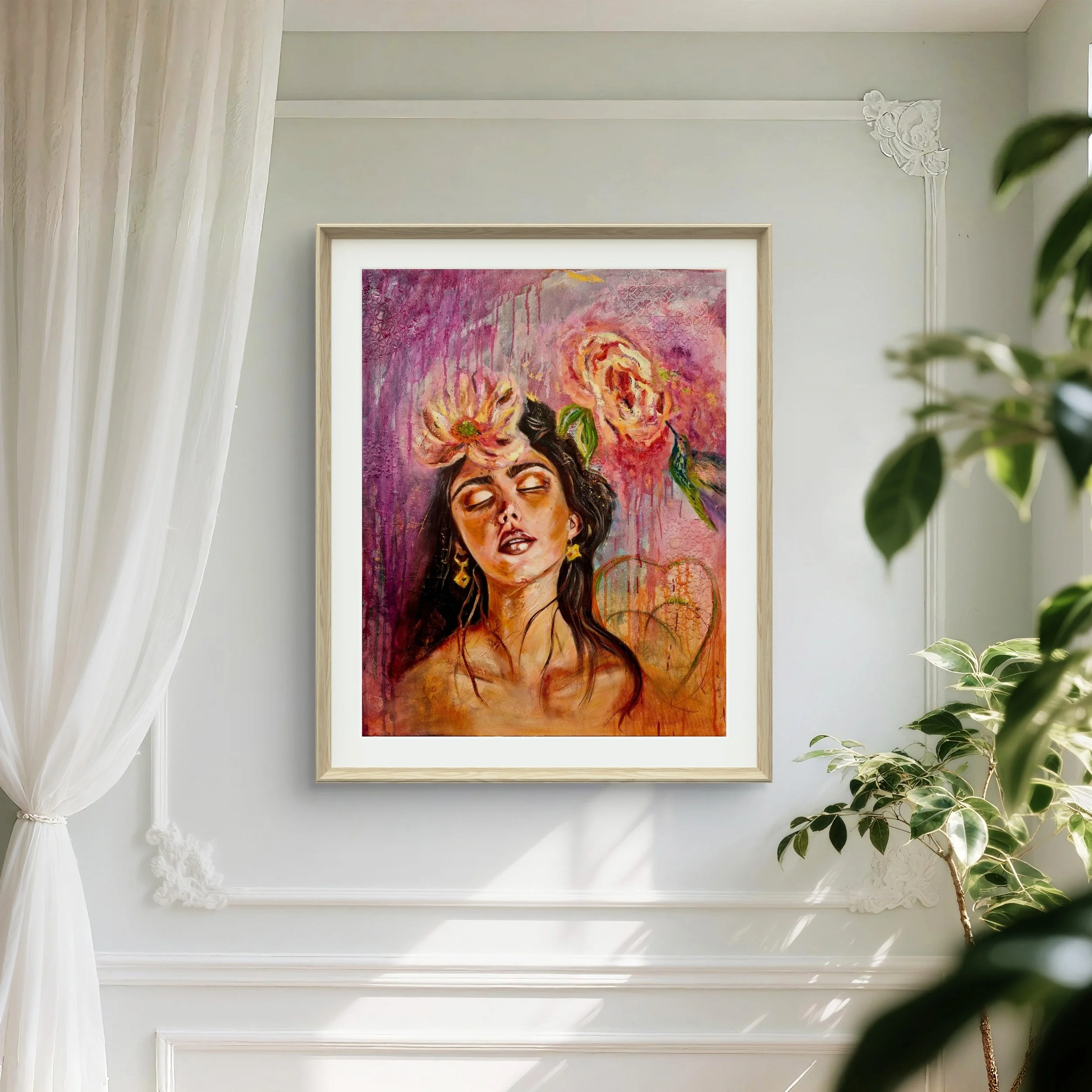 A framed painting of a woman with closed eyes, dark hair, gold earrings, and flowers in her hair. The background features pink, purple, and orange hues with abstract shapes and floral elements, hung on a white wall with decorative molding, beside a window with sheer curtains and a green potted plant.