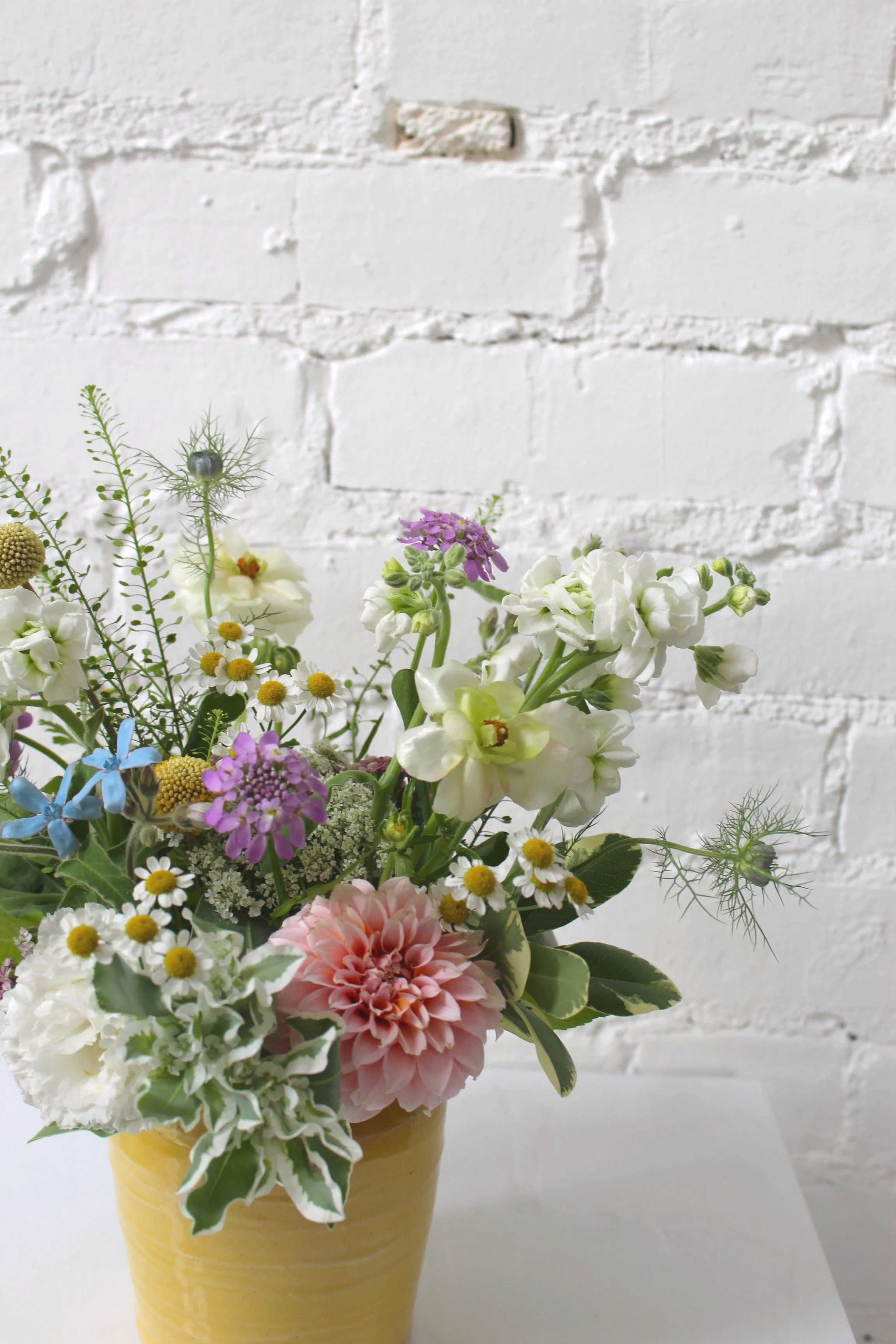 soft colored flowers arranged in a vase decoupaged with baby book pages