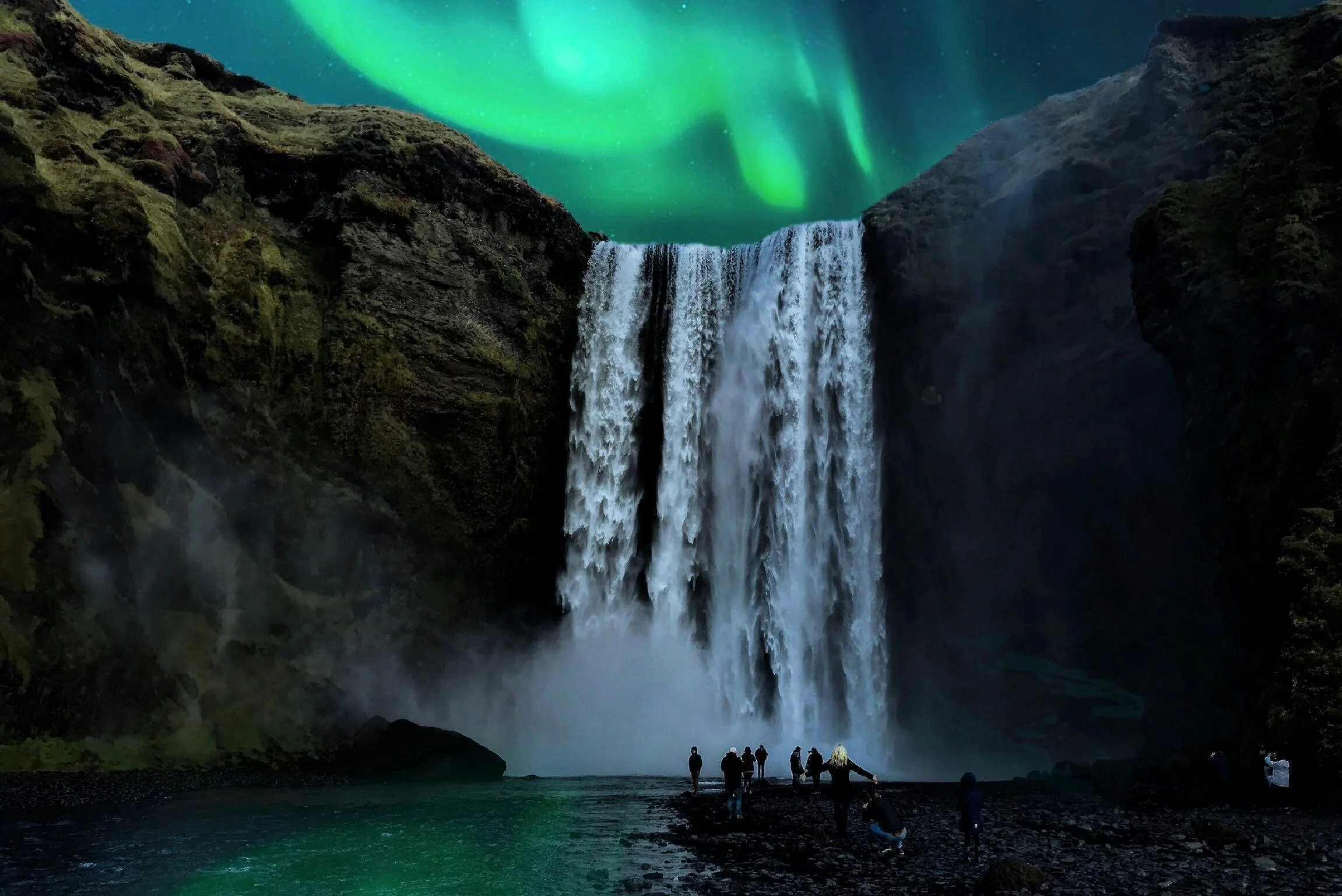 Night scene of a large waterfall with multiple people standing on the rocks at the base, overlooking the waterfall. The sky above is illuminated by the Northern Lights, displaying green and blue auroras.