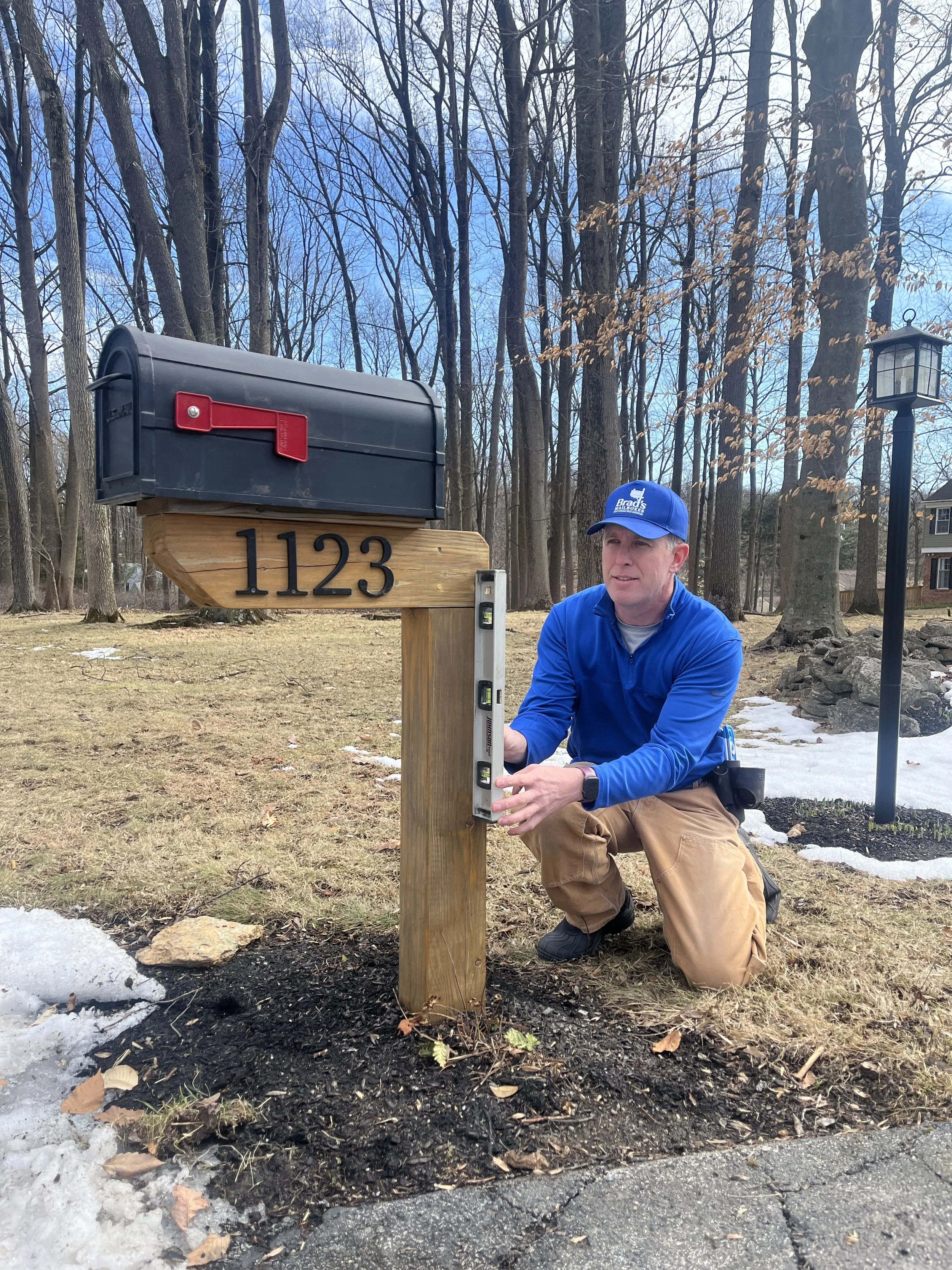 Brad using a level to ensure a mailbox post is level and plumb