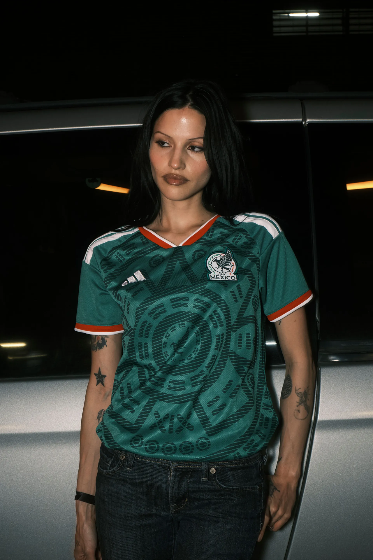 Artist Gabbriette posing wearing a green Mexico soccer jersey and jeans.