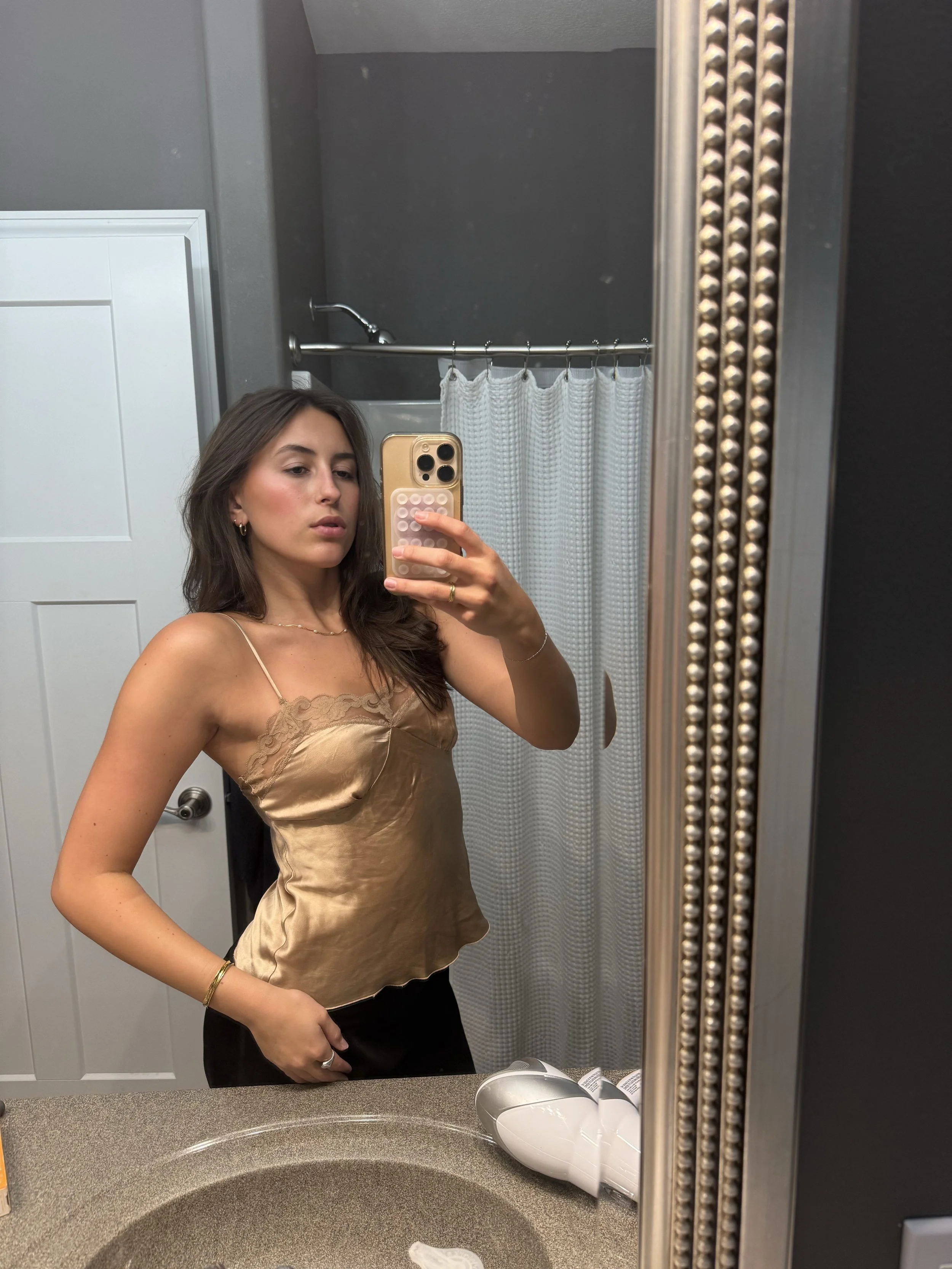Photo of a young woman in a cami top posing in front of a mirror after swapping an item on BONNEE the clothing swap app fashion tech