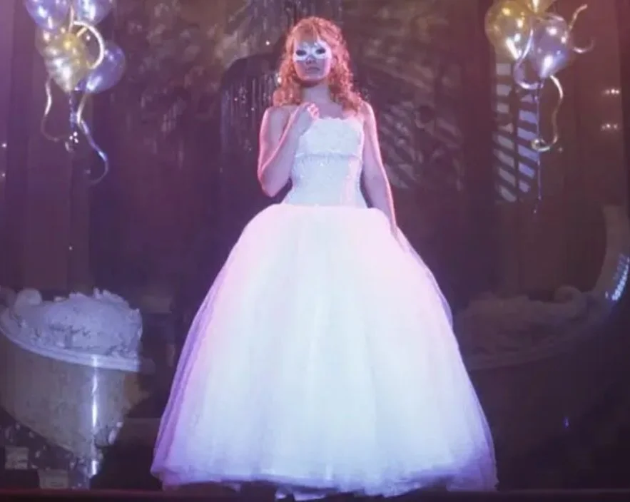 Scene from the movie "A Cinderella Story" in which the main character is at the masquerade ball wearing a puffy gown and mask.