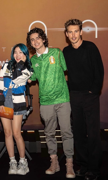 Image of actor Timothee Chalamet at the Dune movie premiere wearing a Mexico soccer jersey. He is in between two other actors.