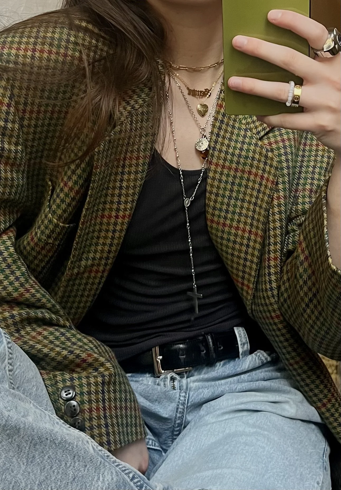 Mirror selfie in a vintage olive houndstooth tweed blazer layered over a black ribbed tank, with light-wash jeans, a black leather belt and layered gold necklaces